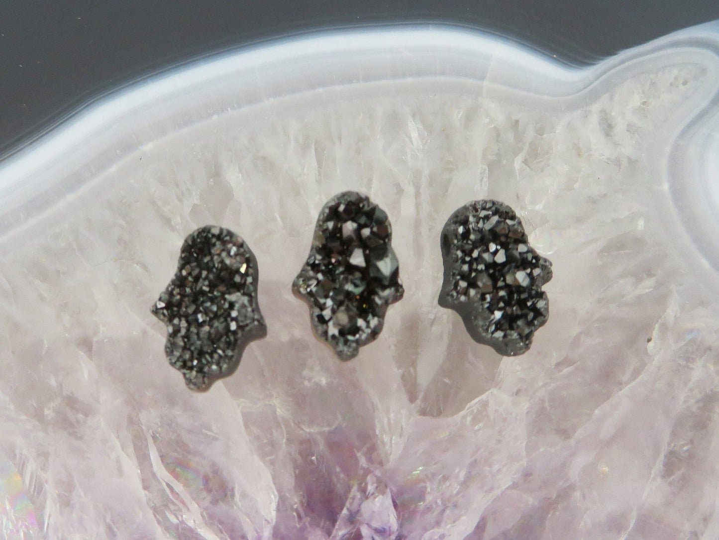 head drilled hamsa bead titanium druzy in assorted color shown against light backgrounds