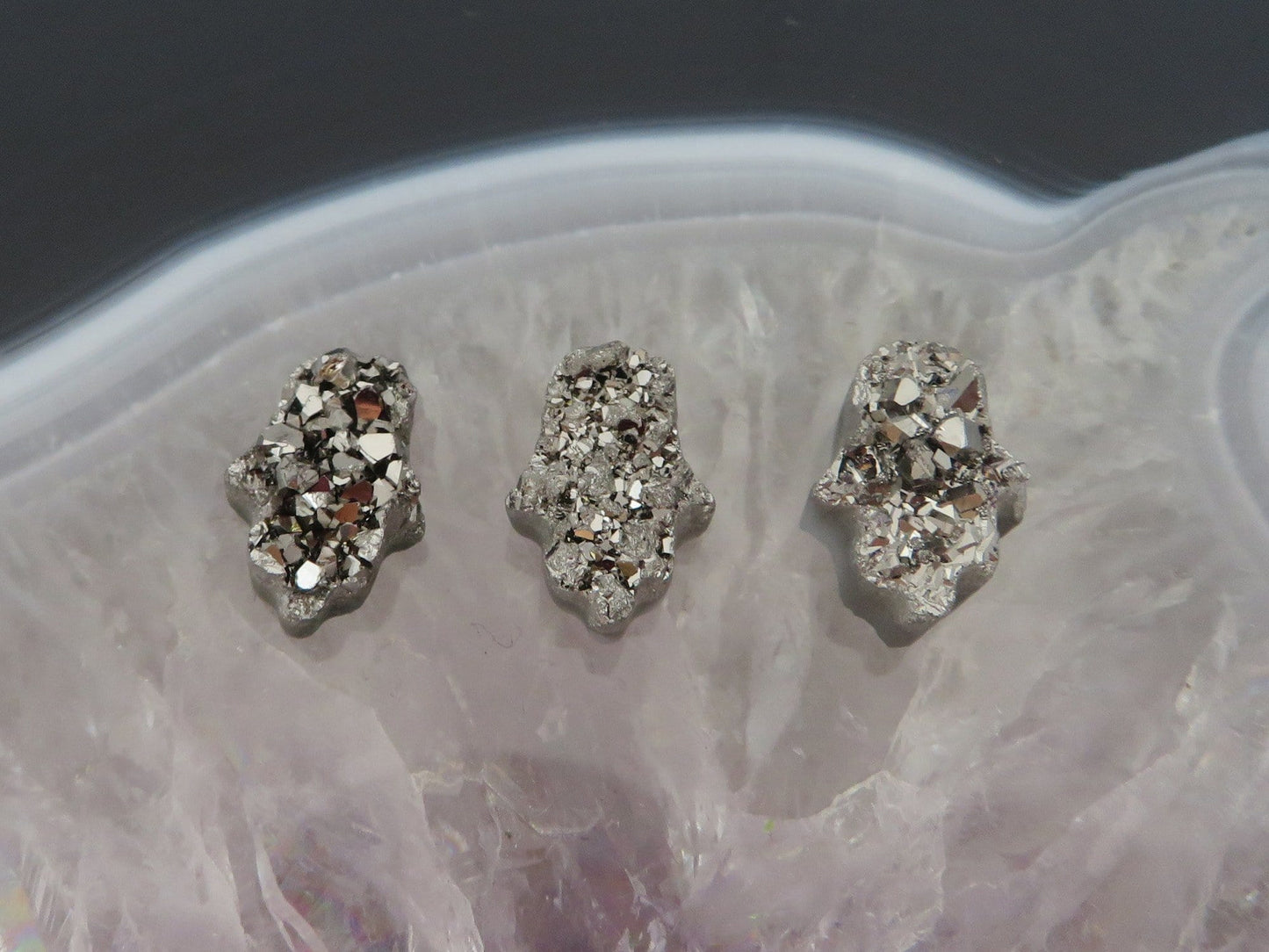 head drilled hamsa bead titanium druzy in assorted color shown against light backgrounds