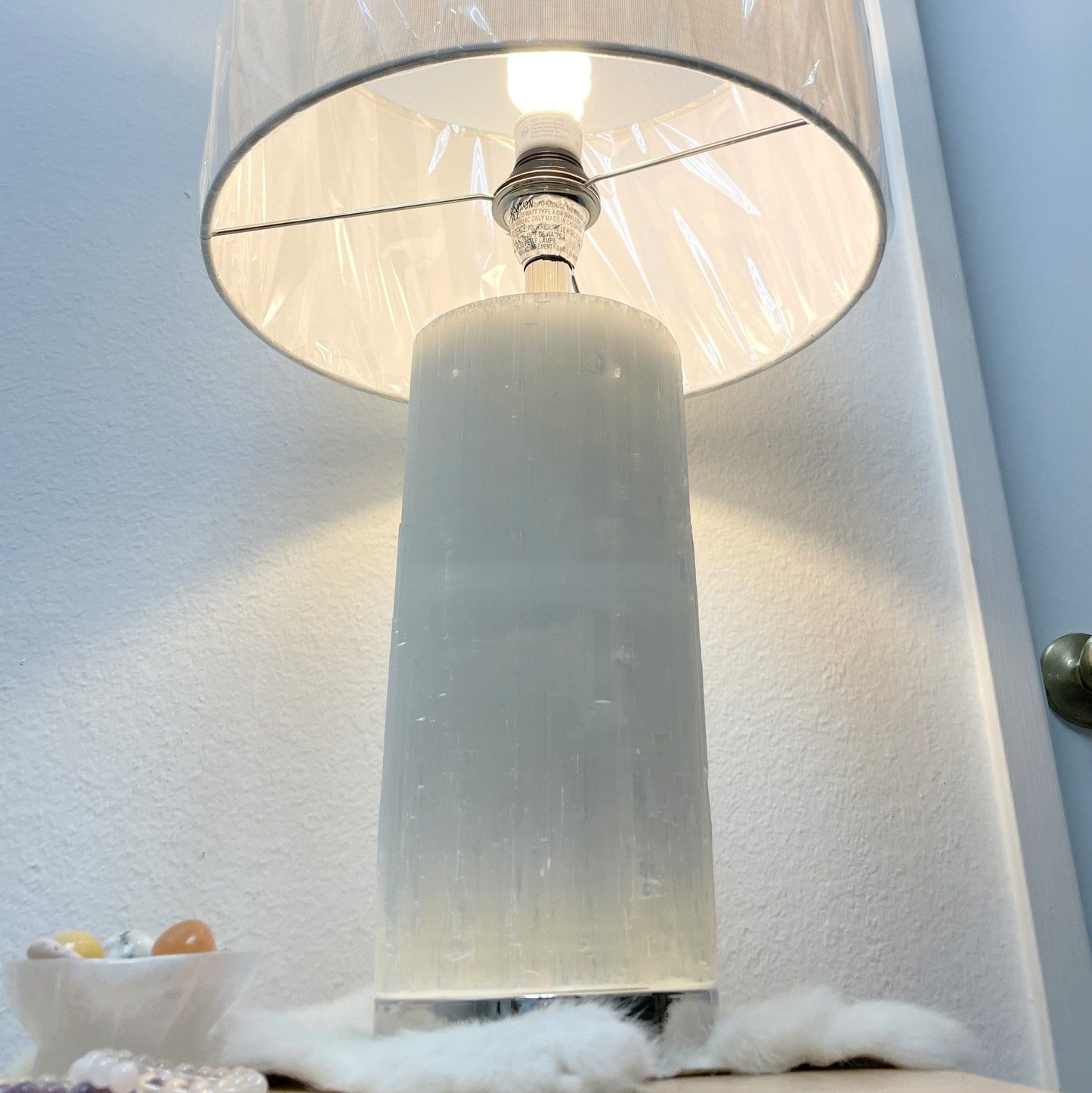angled view of selenite lamp with silver base turned on in the dark