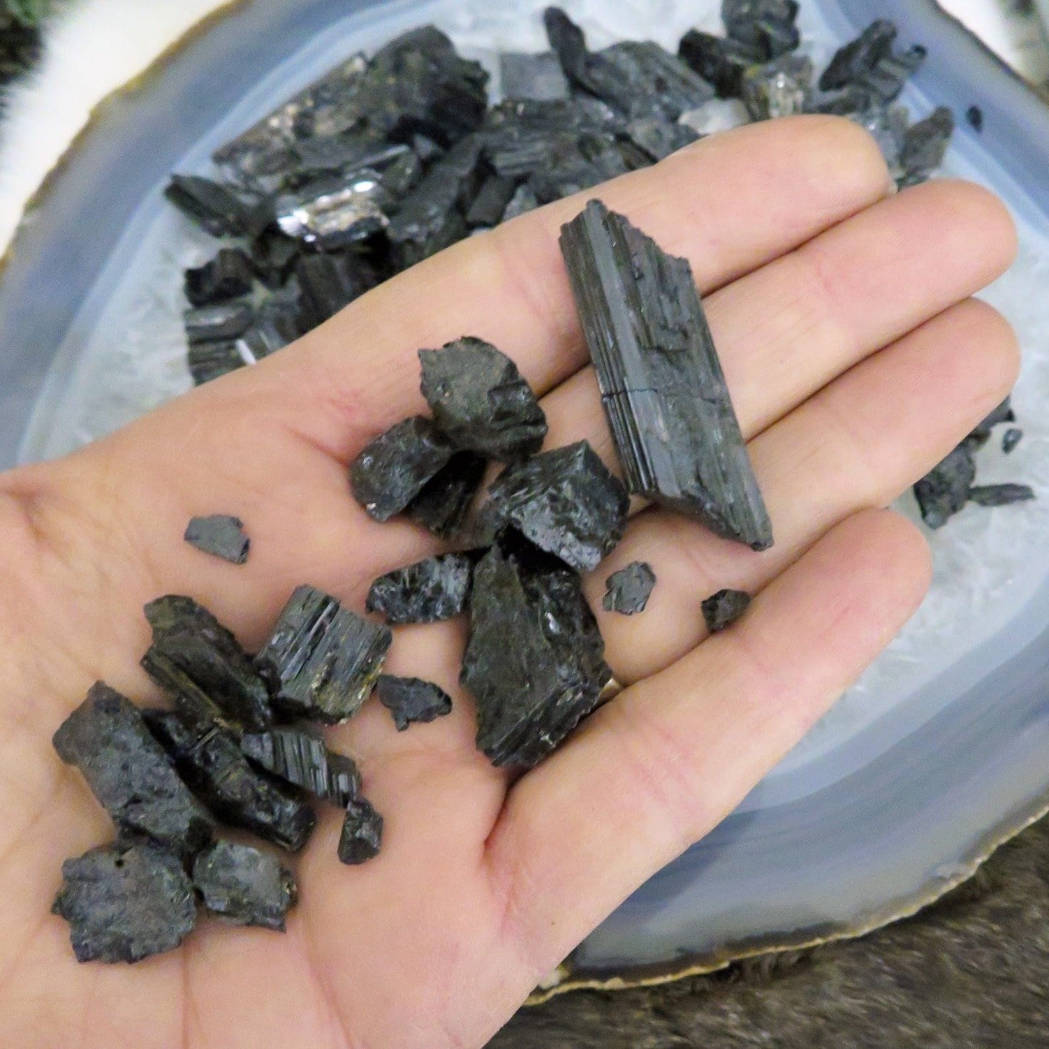 black tourmaline chips in hand for size reference