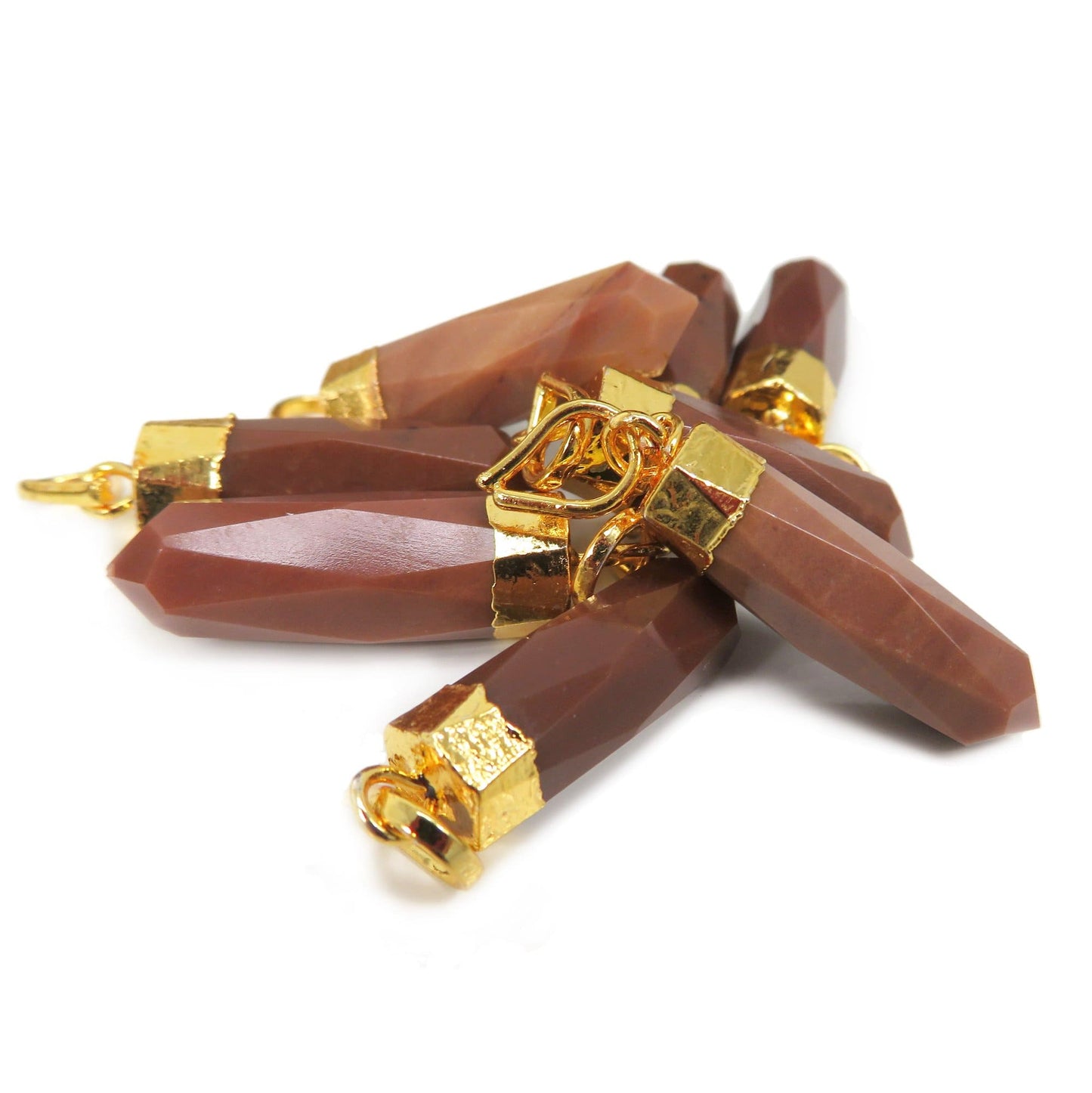 A pile of Jasper Spike Pendants with gold electroplated cap, laying on a table