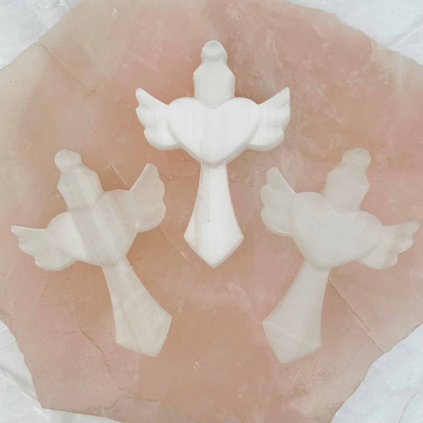 multiple carved selenite crosse displayed to show the slight differences in the sizes