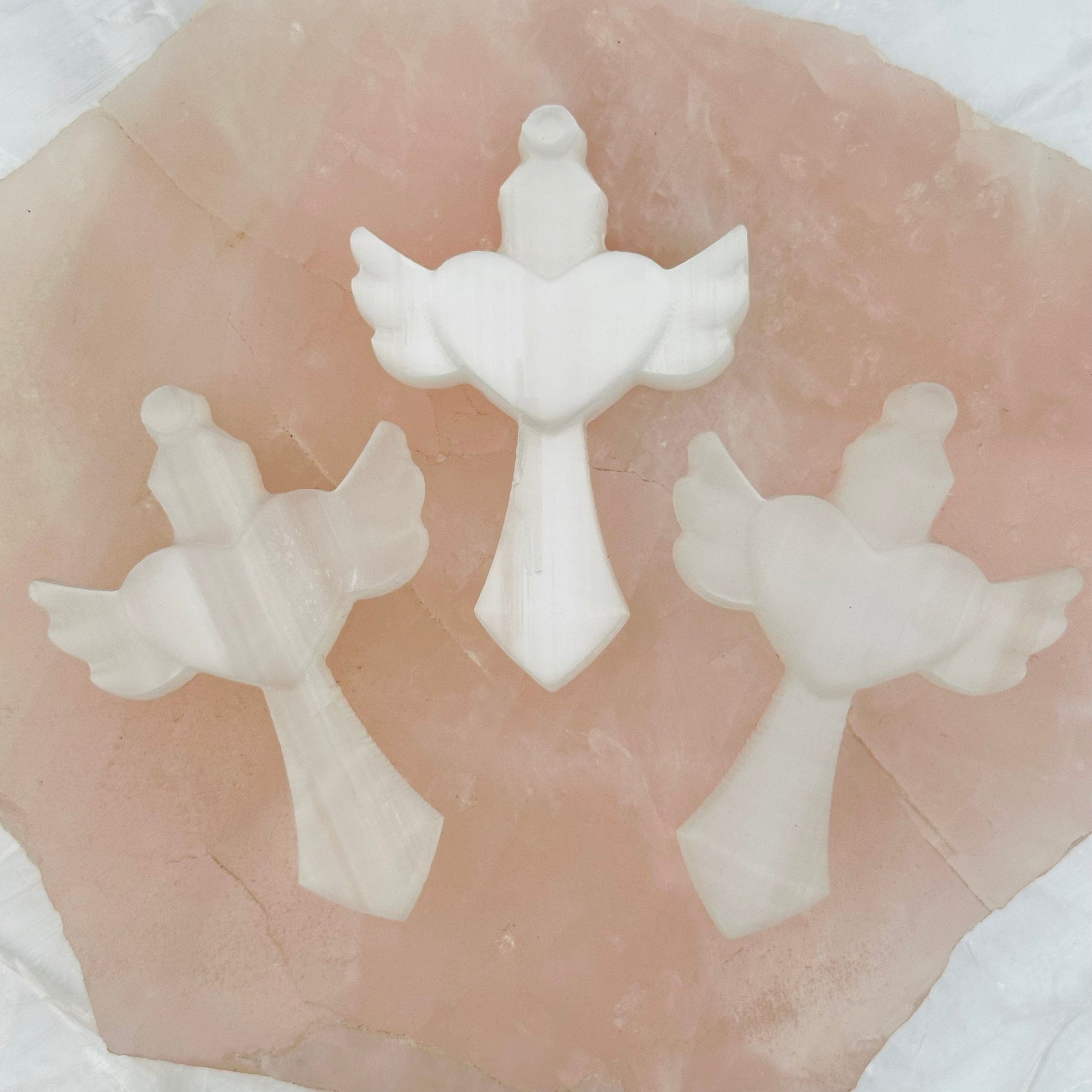 multiple carved selenite crosse displayed to show the slight differences in the sizes