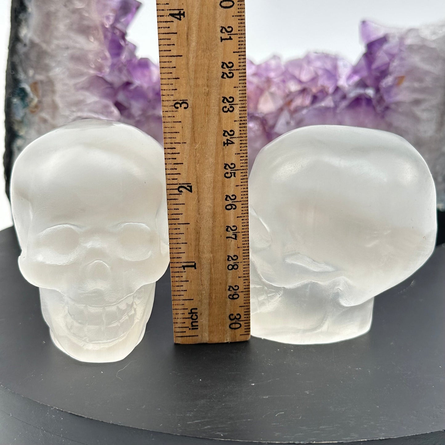 selenite crystal skulls displayed next to a ruler for size reference 