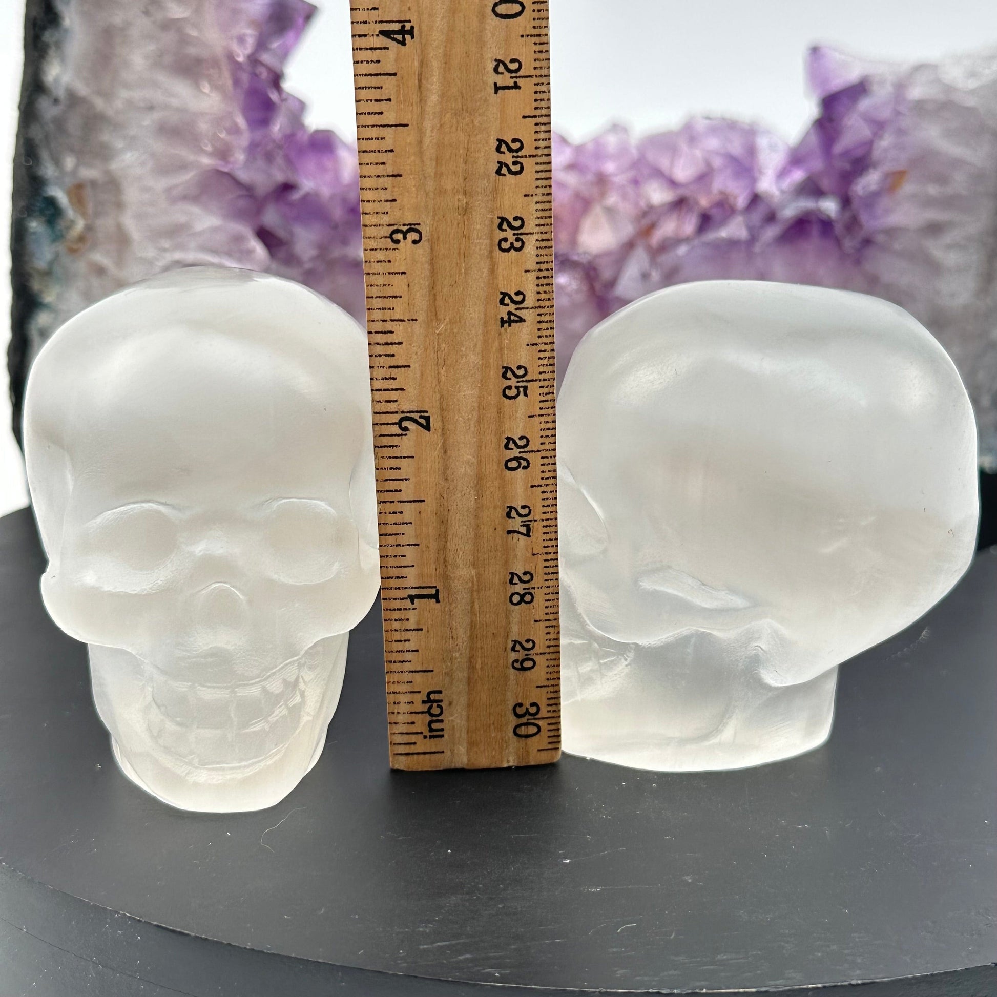 selenite crystal skulls displayed next to a ruler for size reference 