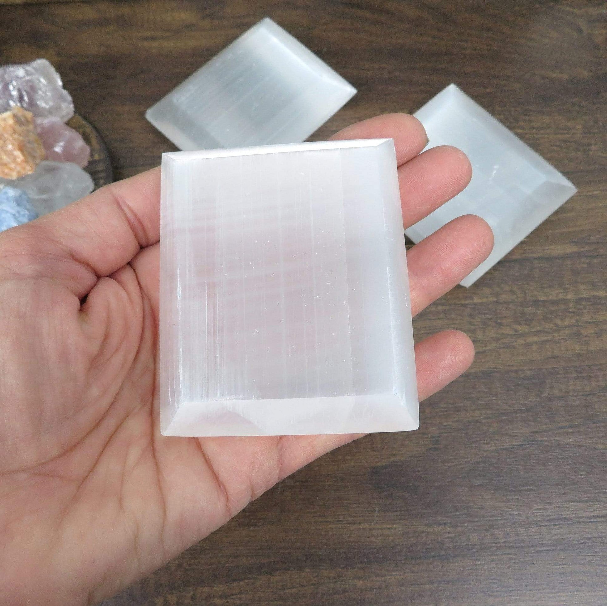 selenite square charging plat in hand for size reference with others in background