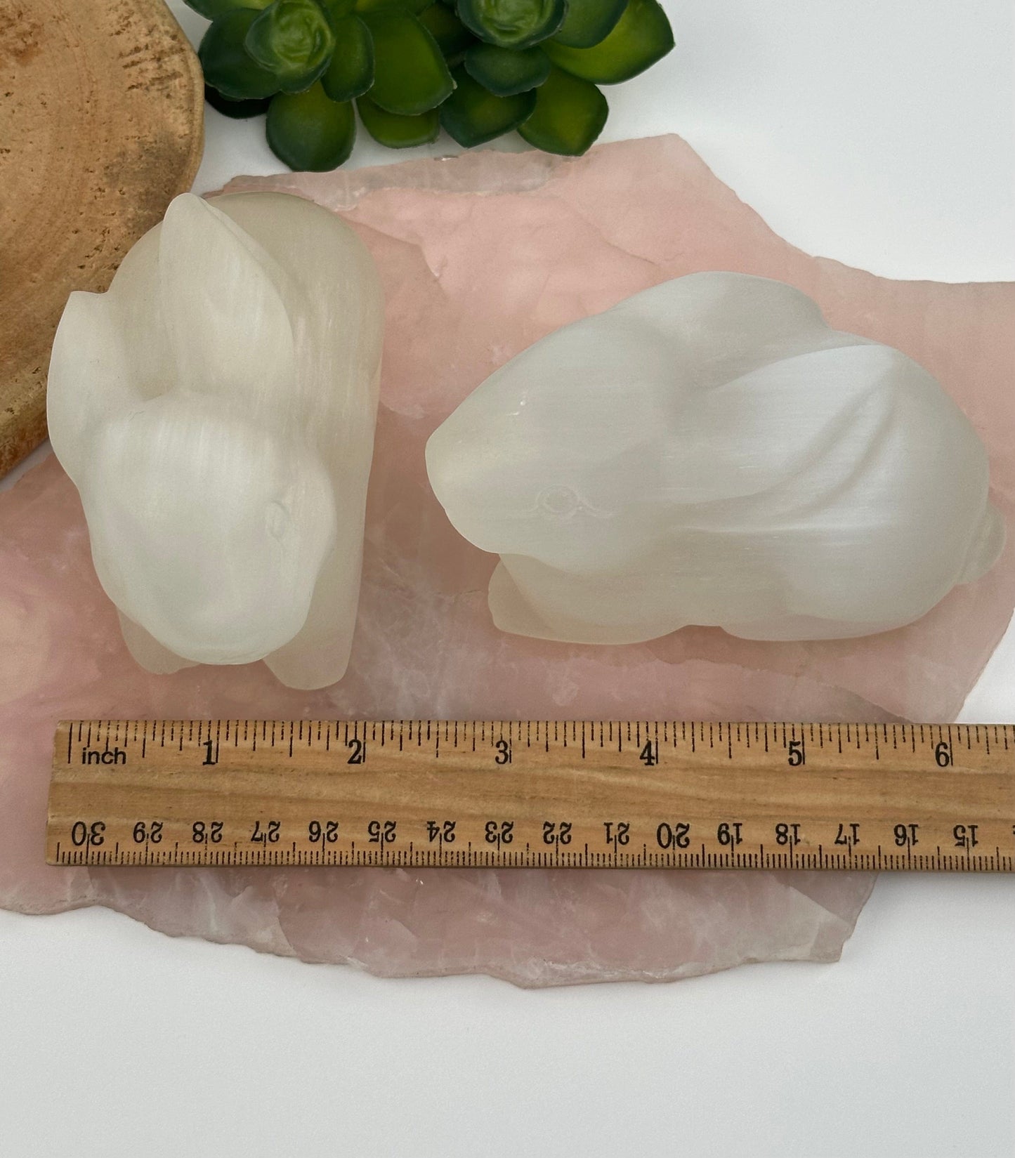 carved selenite next to a ruler for size reference 