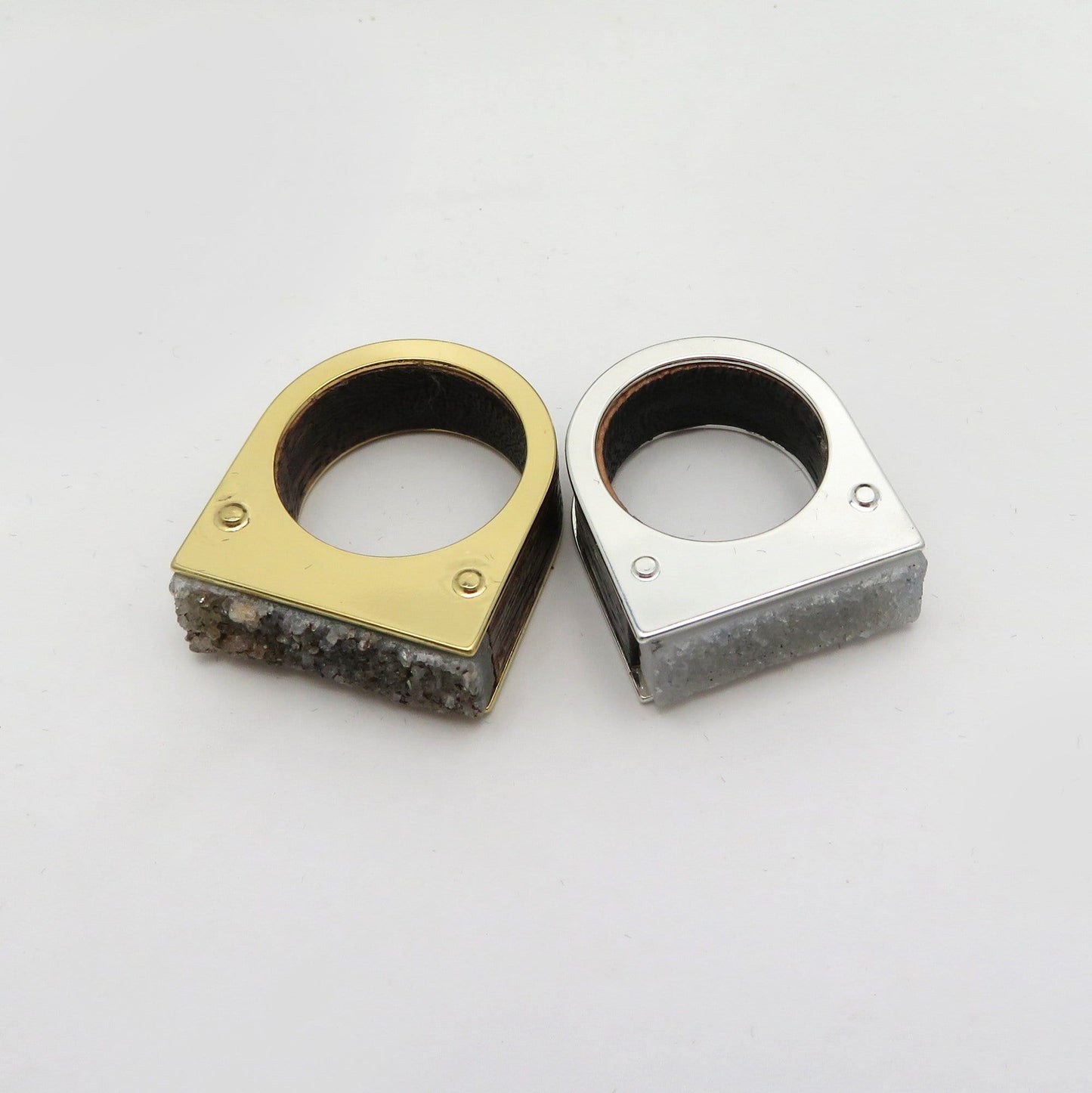 Two druzy rings on a white background.  One is gold plated and the other silver plated.  The druzy is gray in one and dark gray in another.