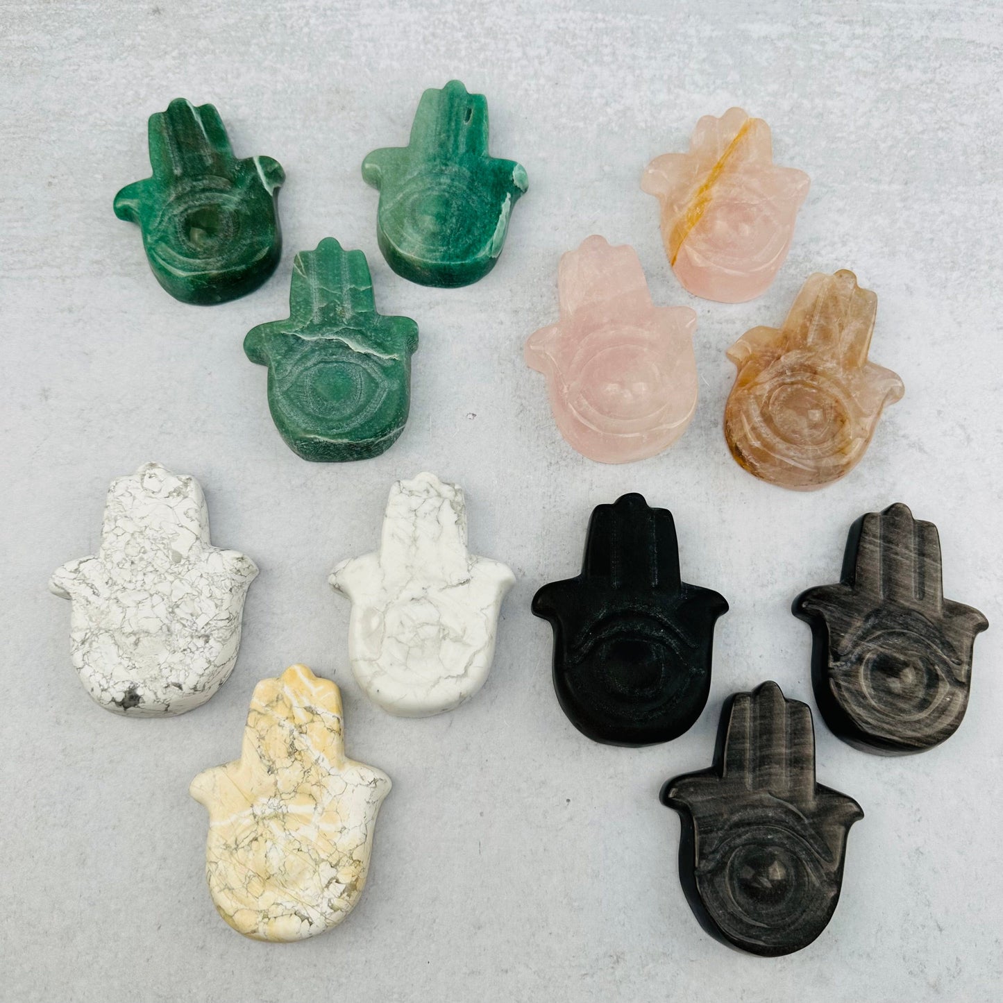 multiple Carved Hamsa Hand Stone with Protective Eye displayed to show the differences in the color shades 