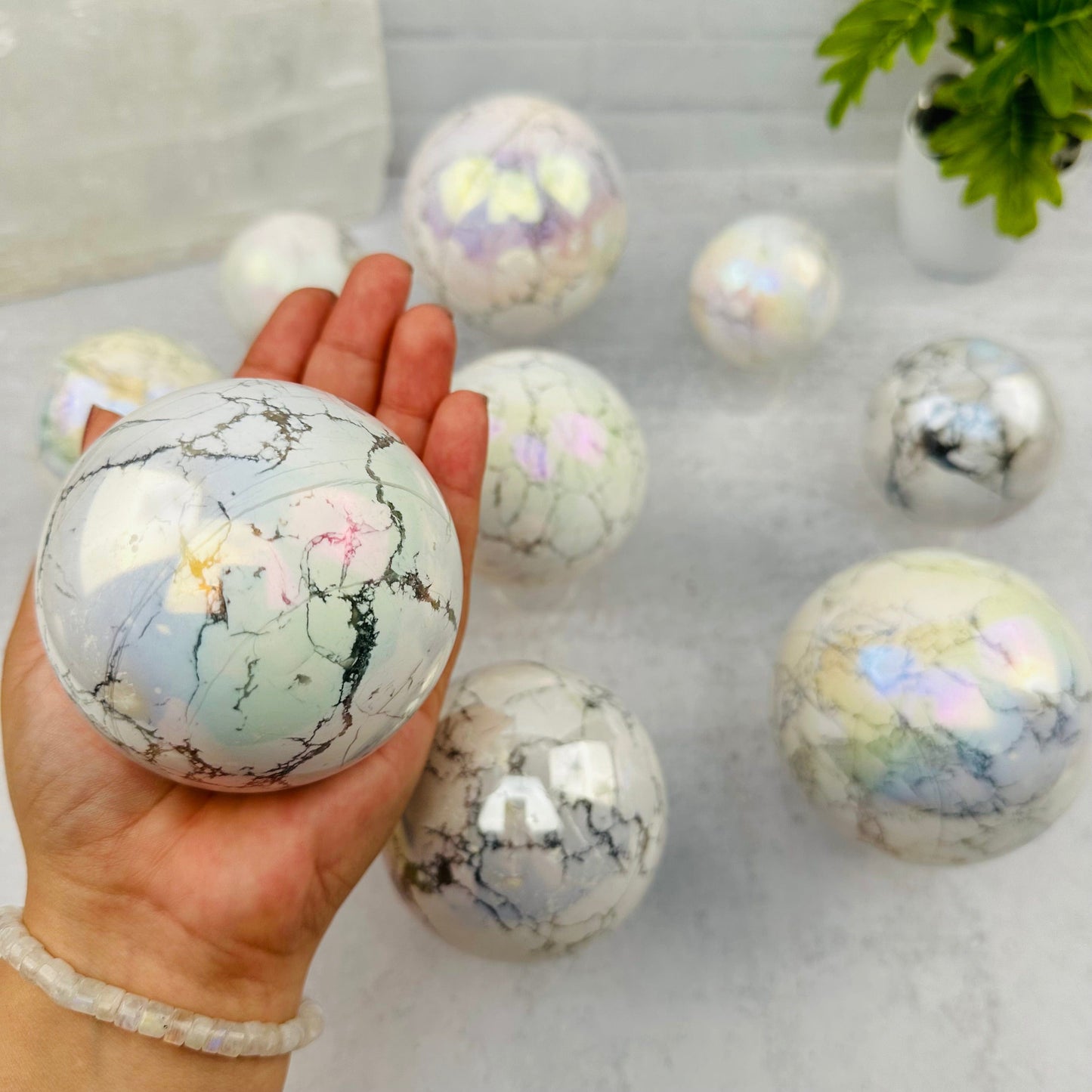 White Howlite Angel Aura Polished Sphere in hand for size reference 