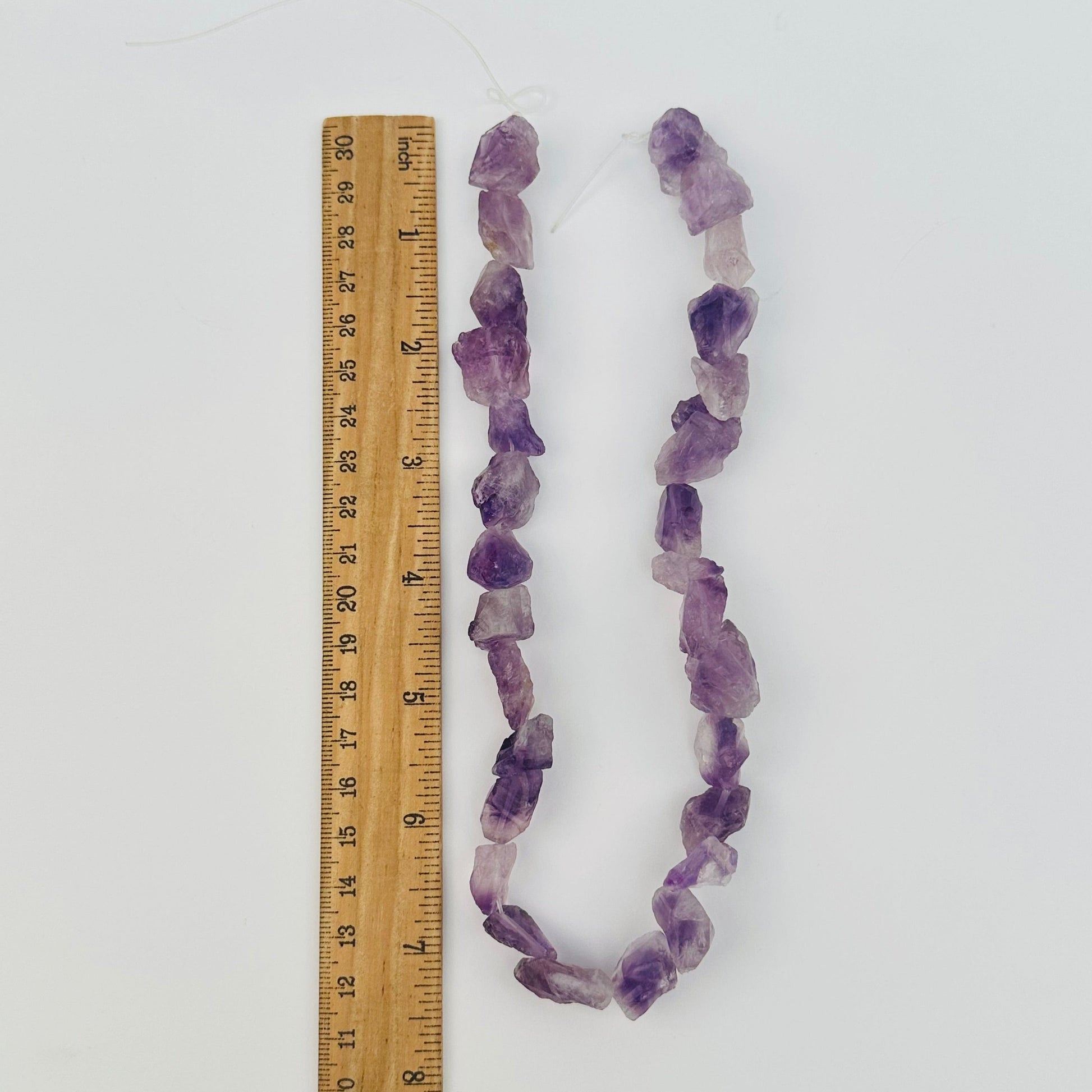 amethyst crystal beads next to a ruler for size reference 