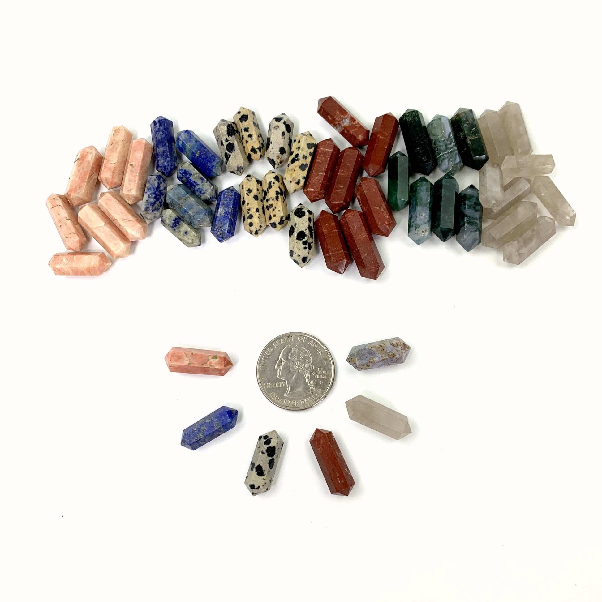 6 Gemstones in a Half Circle Surrounding a Quarter With 6 Piles of Gemstones Behind on a White Background.