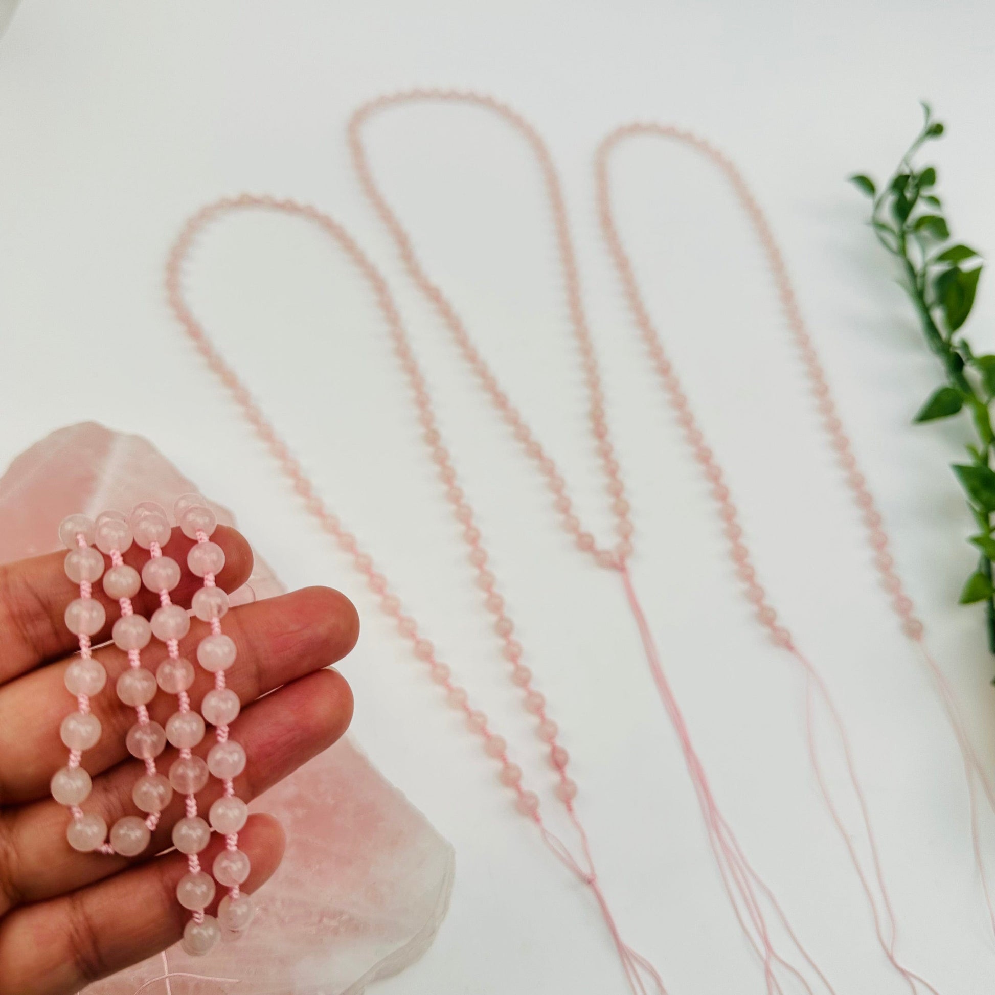 rose quartz mala bead necklace in hand for size reference 