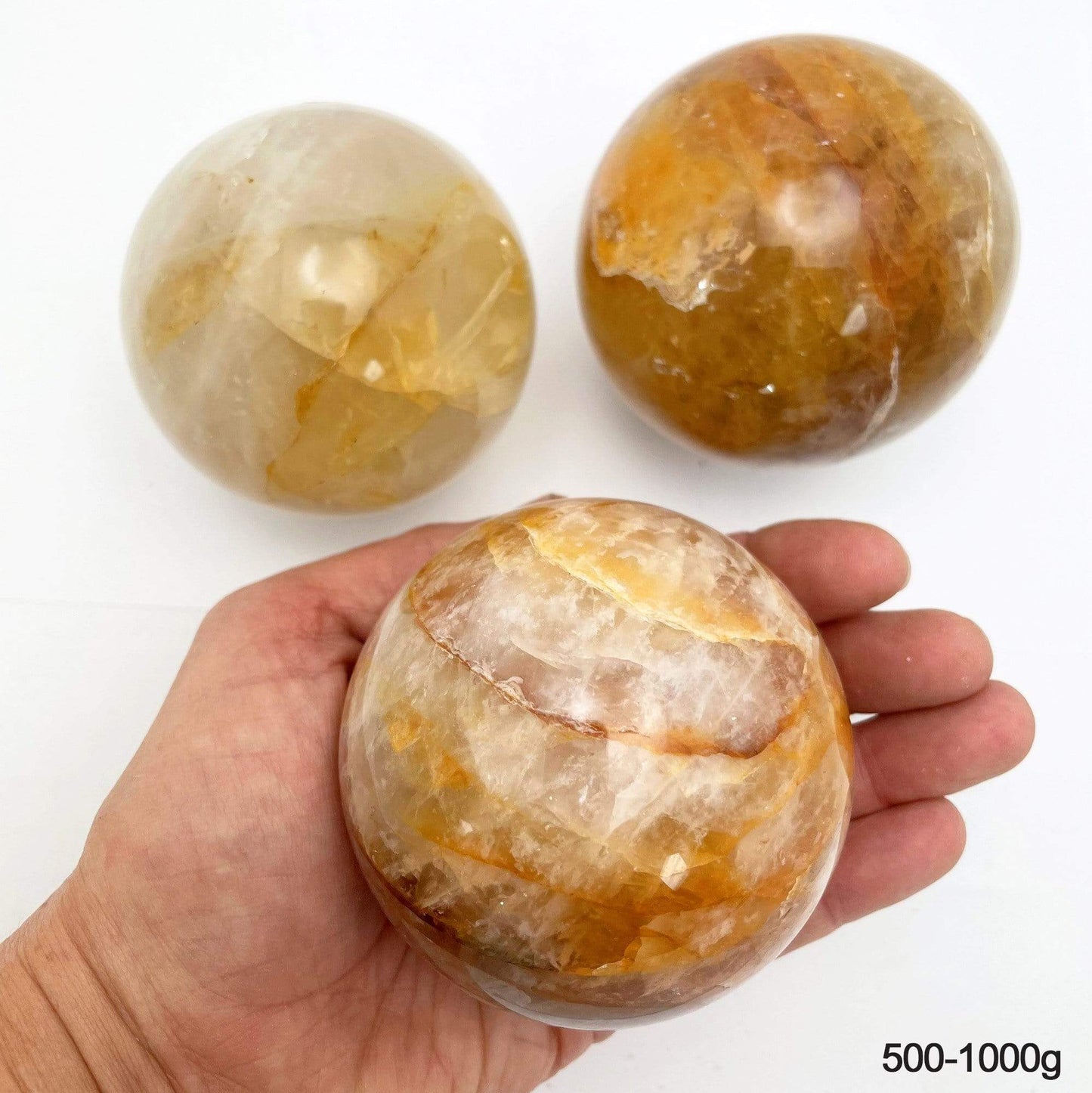 500-1000g golden healer polished spheres on white background