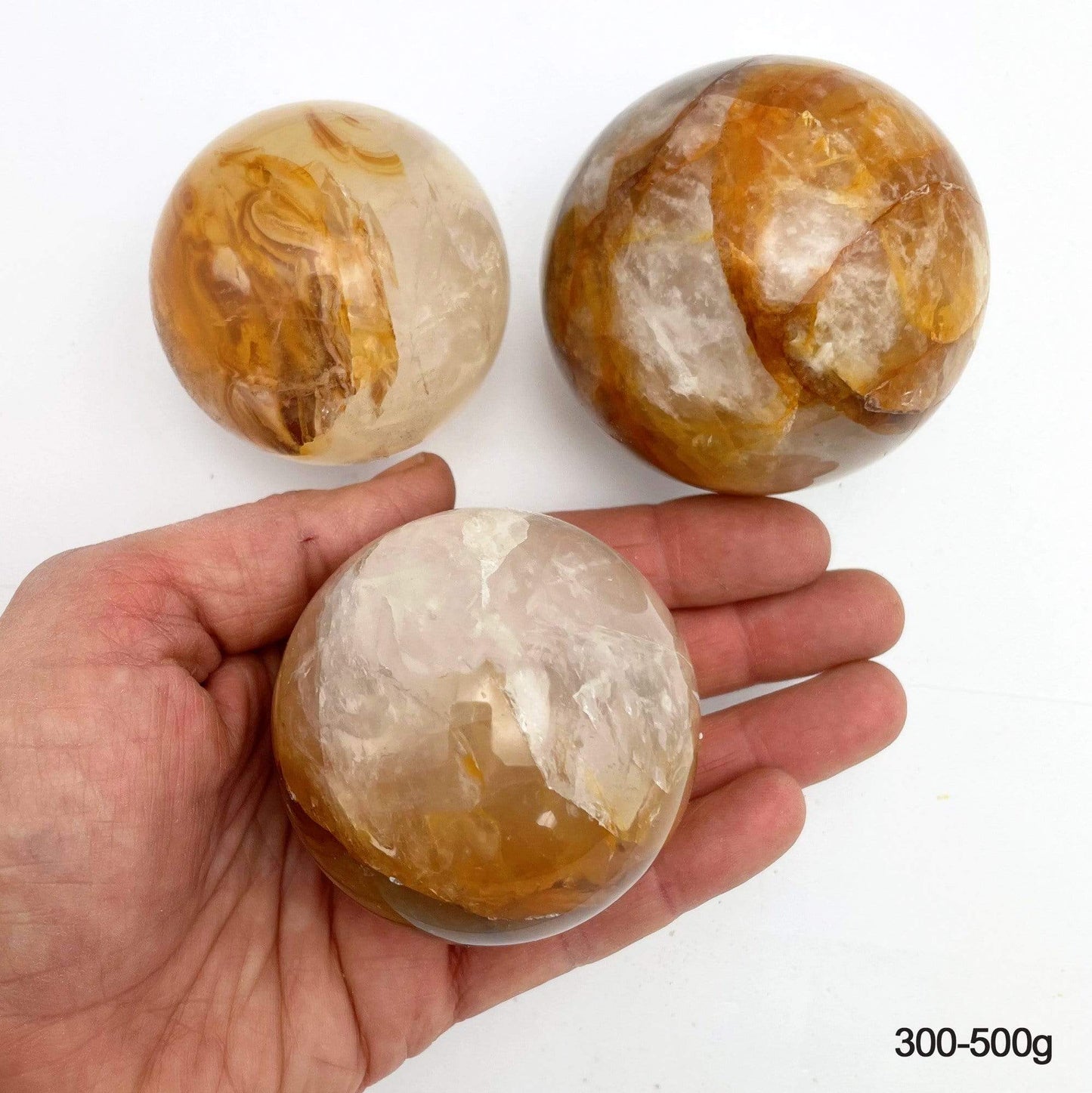300-500g golden healer polished spheres on white background