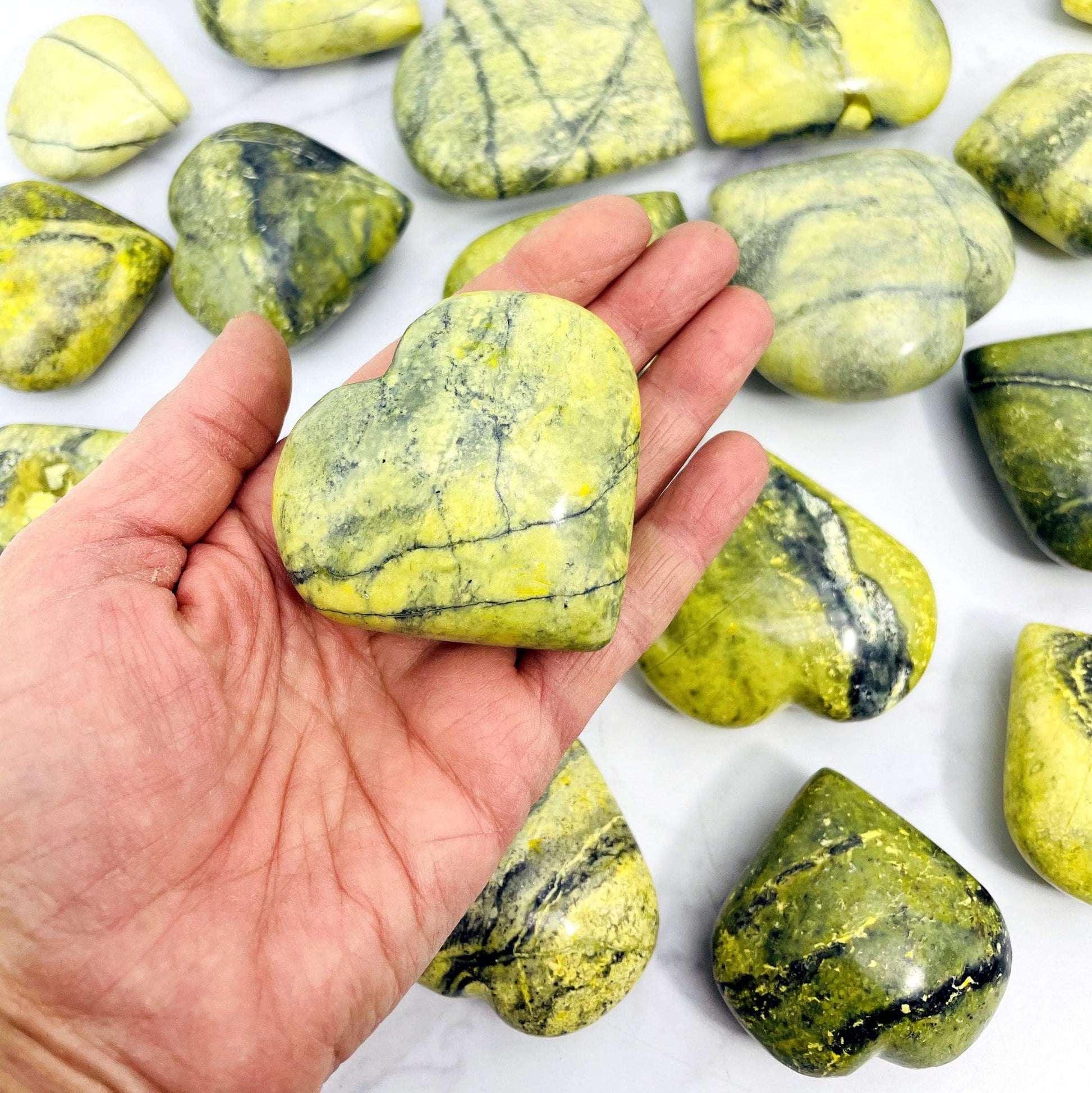 one 100g-200g serpentine polished heart in hand for size reference with others in background