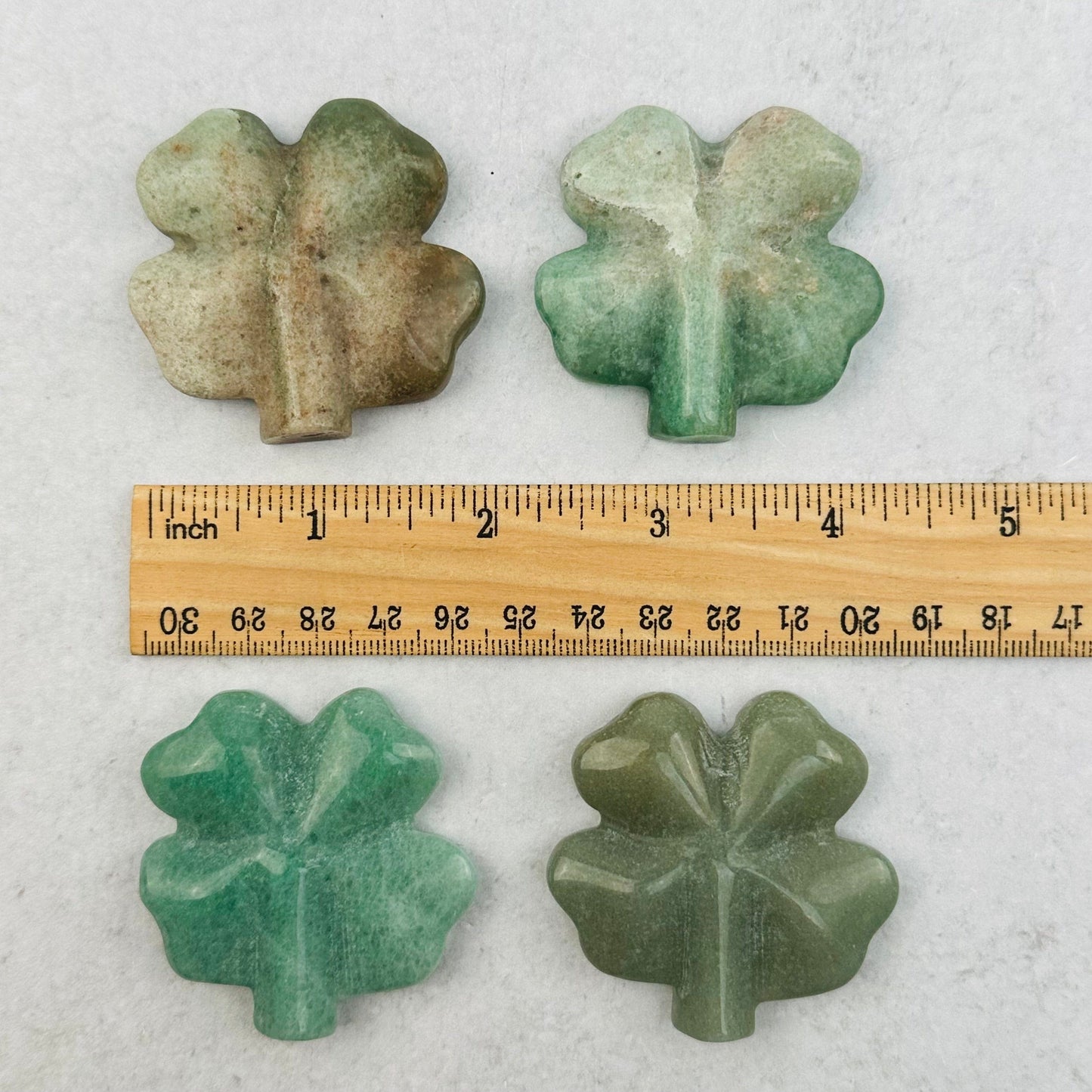 Green Aventurine Carved Gemstone Clovers next to a ruler for size reference 