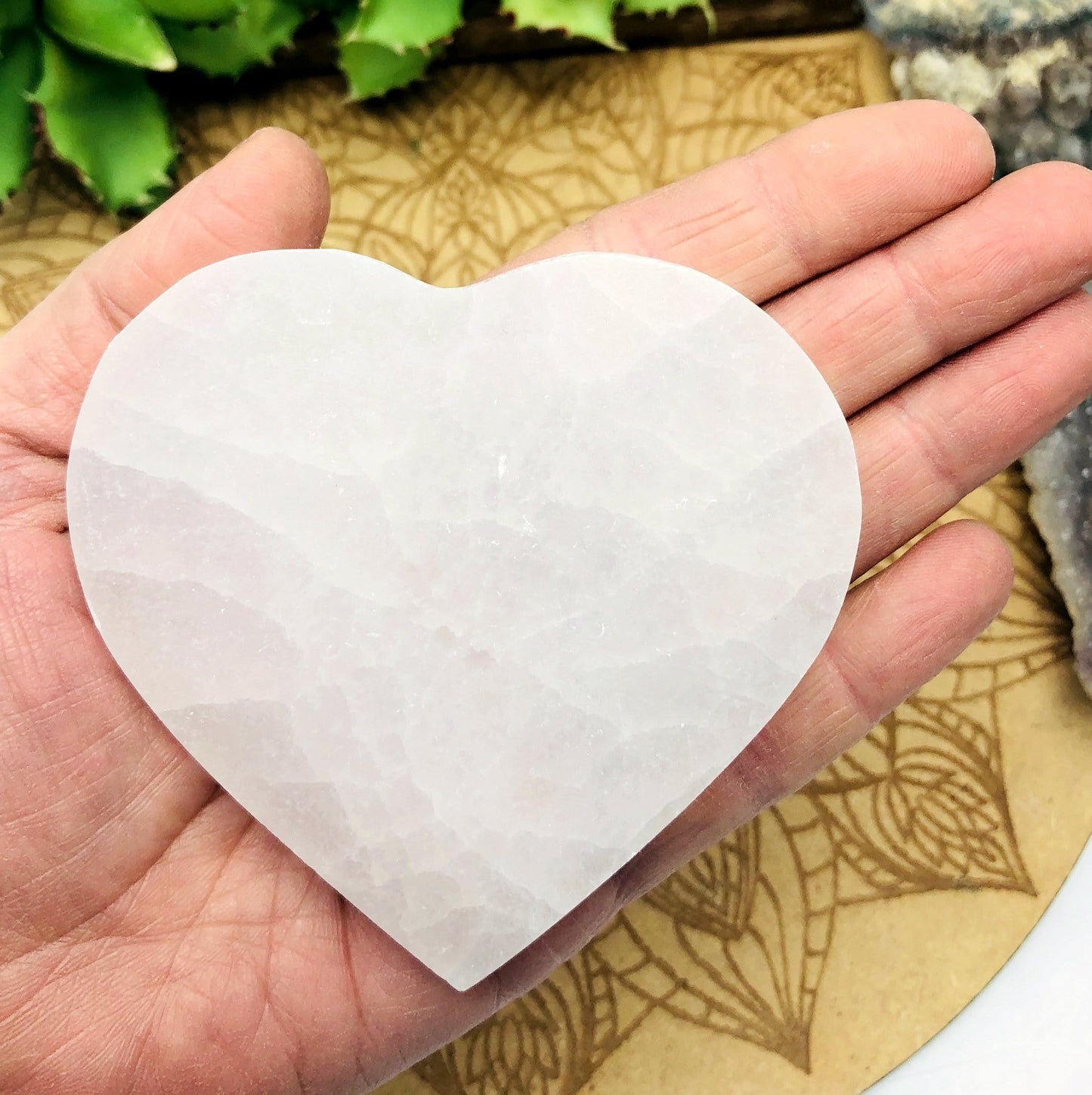 selenite flat heart in hand for size reference