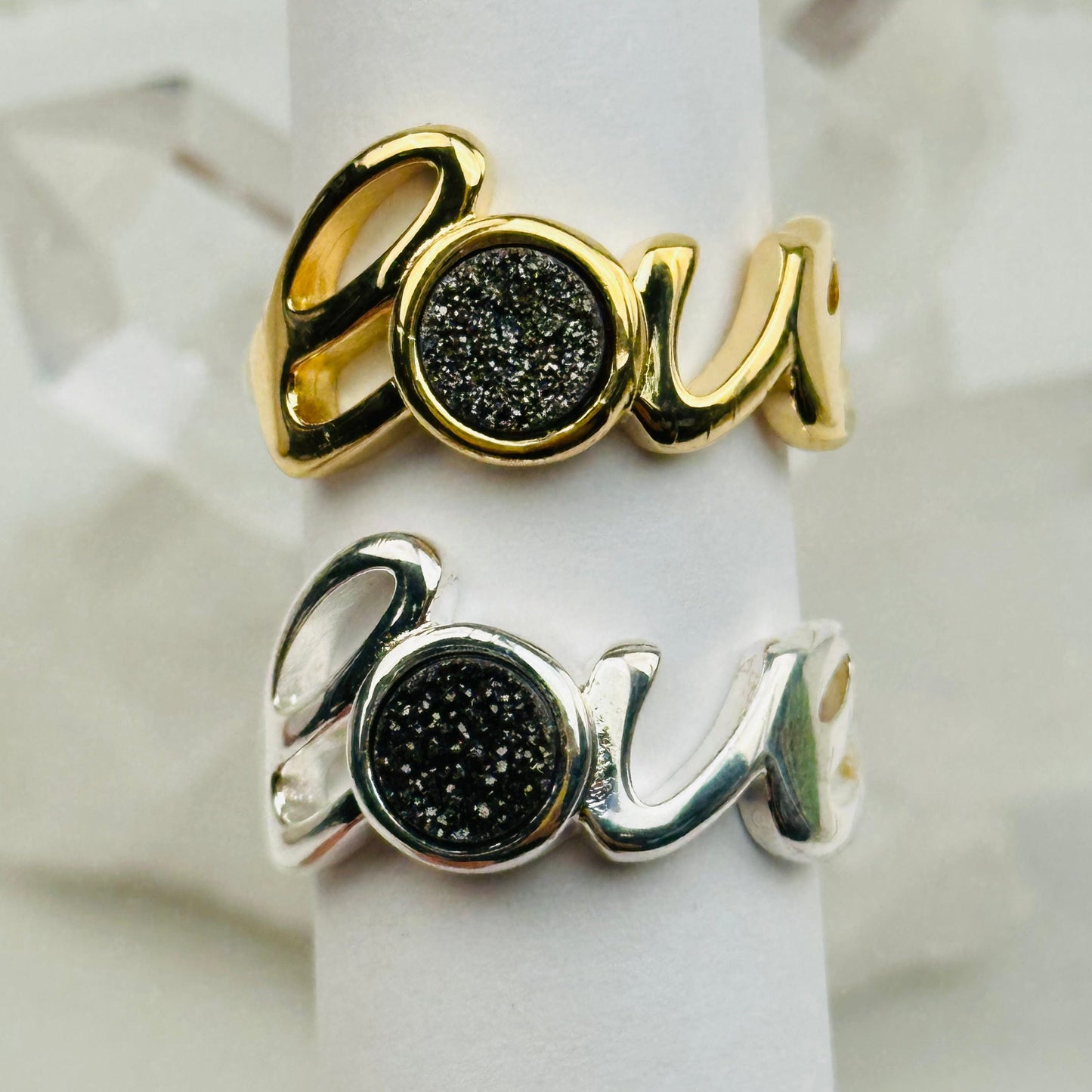close up of the details on these black druzy rings that say the word love