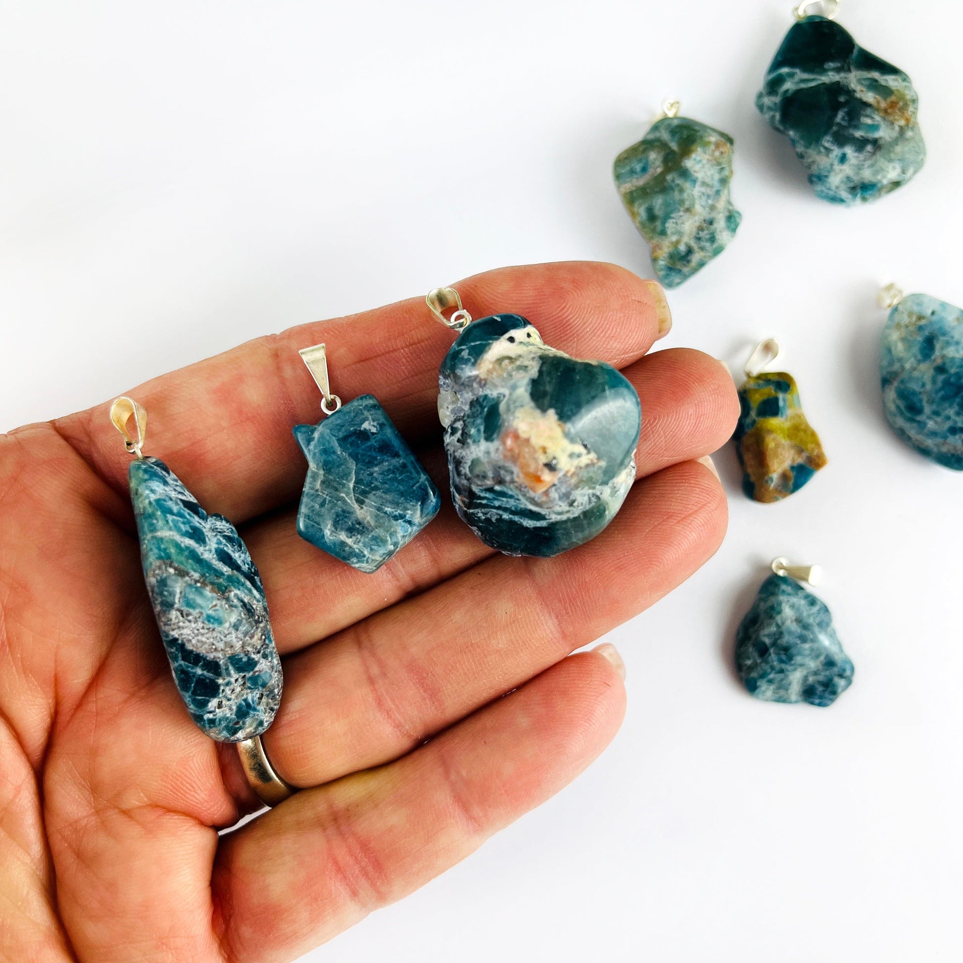 Apatite Polished Freeform Crystal Pendants with Silver Bails in a hand showing various sizes of the stock available