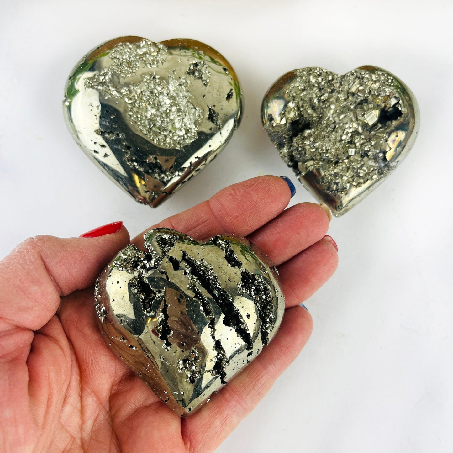 3 Pyrite Crystal Hearts with one in a hand for size reference