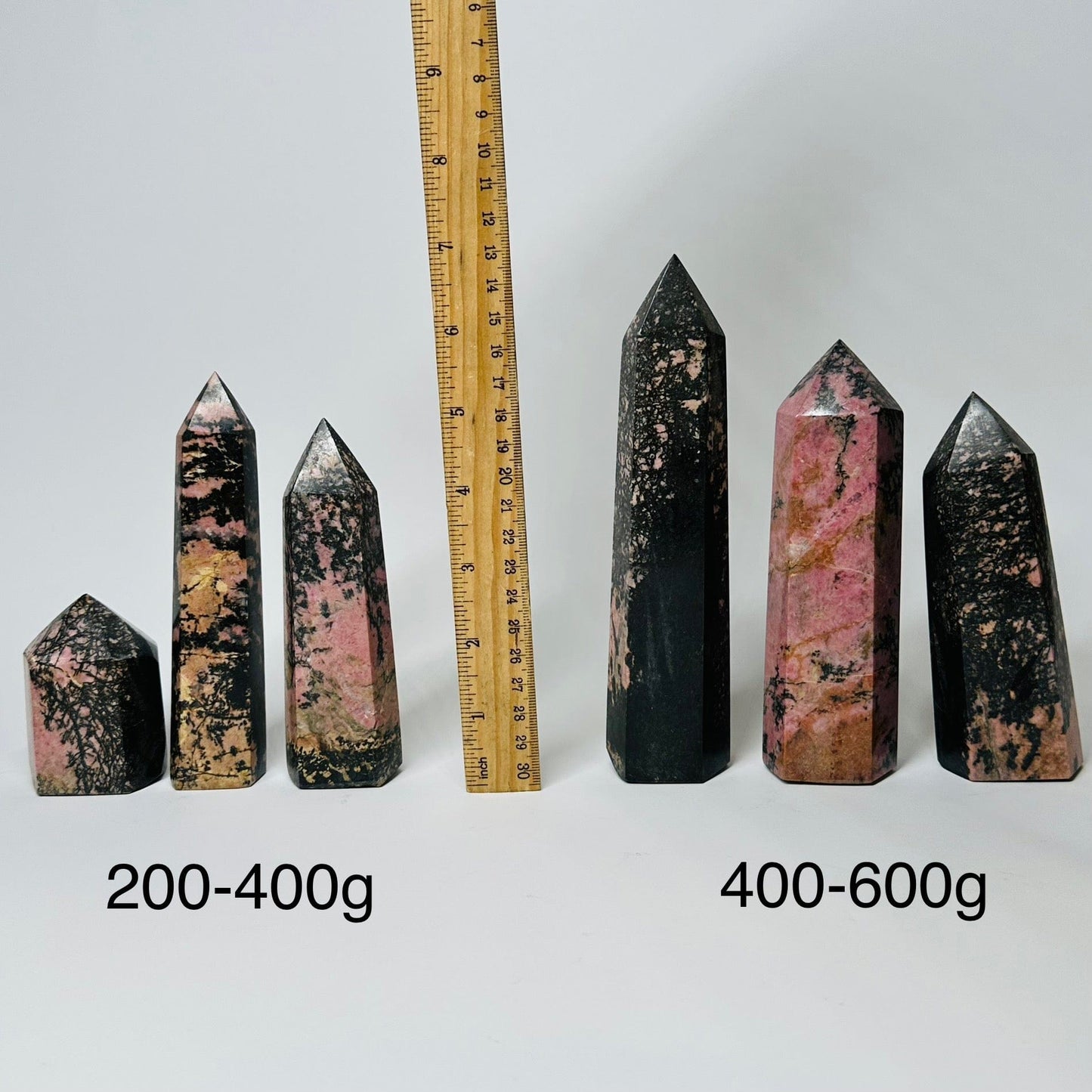 Rhodonite Crystal Polished Points - By Weight - displayed next to a ruler for size reference 