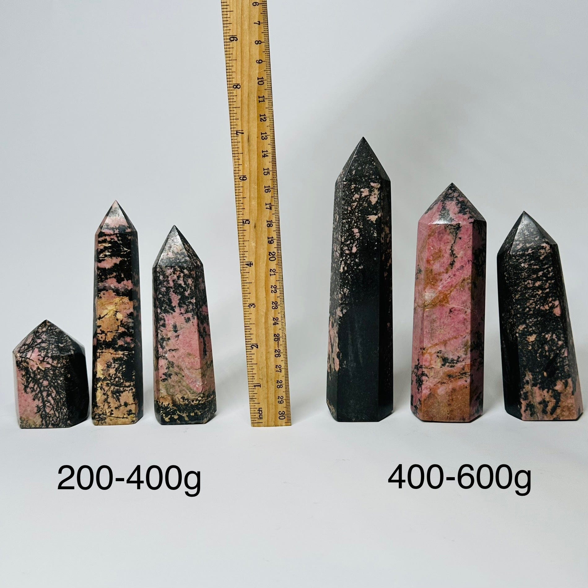 Rhodonite Crystal Polished Points - By Weight - displayed next to a ruler for size reference 