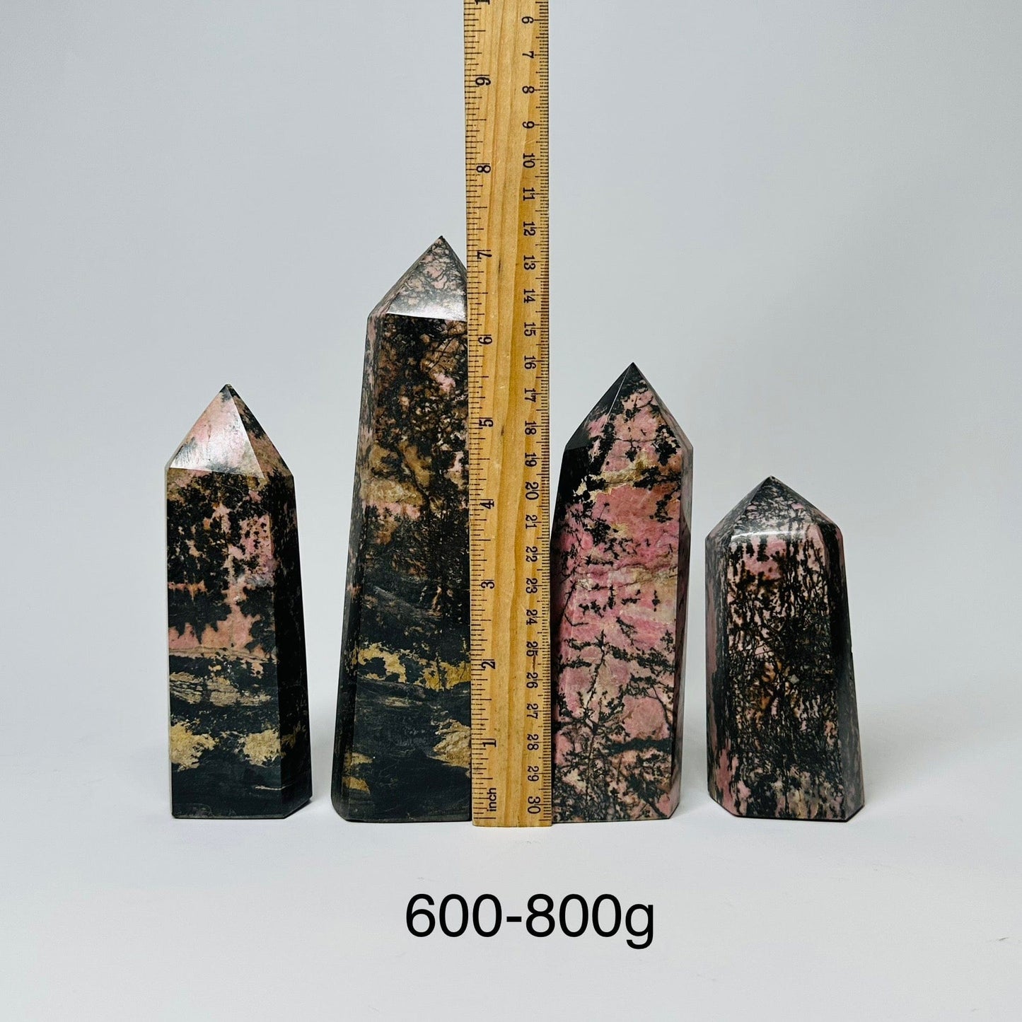 Rhodonite Crystal Polished Points - By Weight - displayed next to a ruler for size reference 