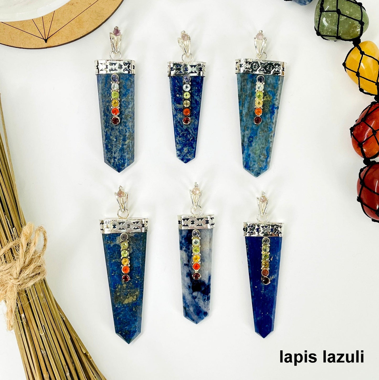 overhead view of six lapis lazuli polished point pendants with chakra gemstone accent for possible variations