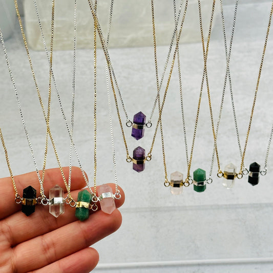 double terminated crystal point necklaces in gold and silver in a hand for size reference