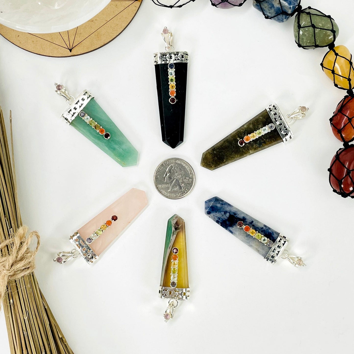 overhead view of one of each polished point pendant options on white background surrounding a quarter for size reference