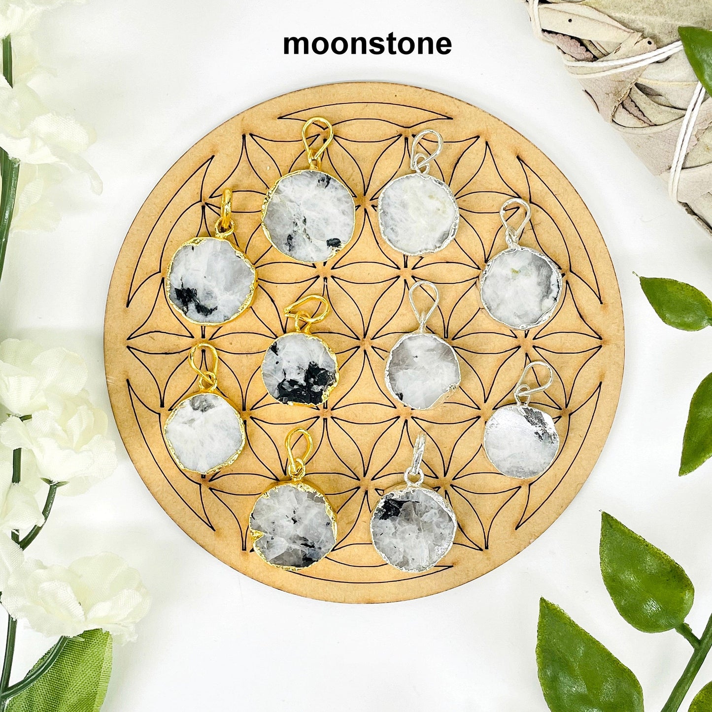 overhead view of five gold and five silver round moonstone pendants on display with decorations for possible variations and finish comparison