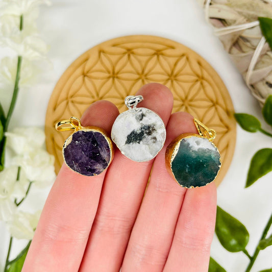 close up of three different round gemstone pendants in hand for size reference and possible options