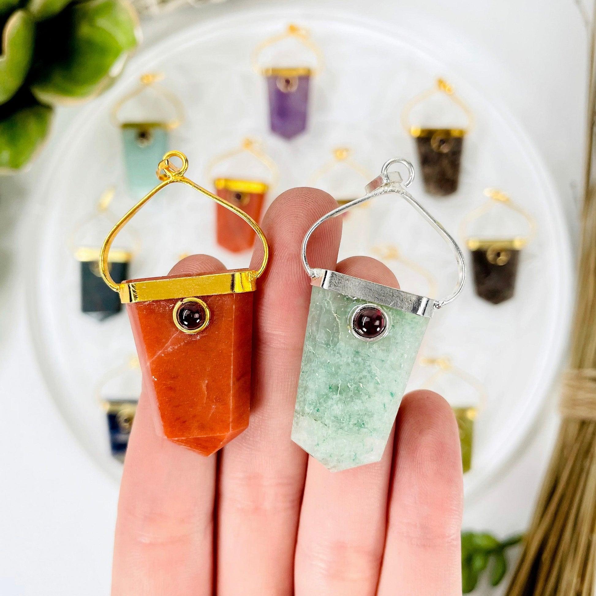 close up of two shield pendants with garnet accent for size reference and possible options