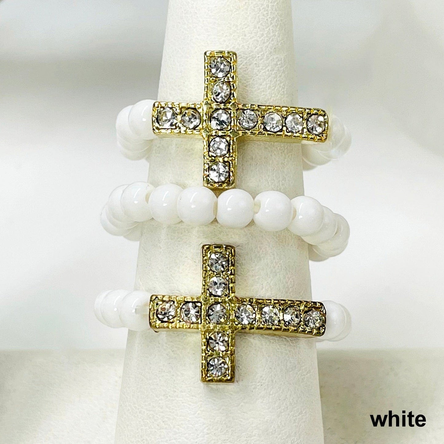 close up of three white sideways cross elastic rings on ring display