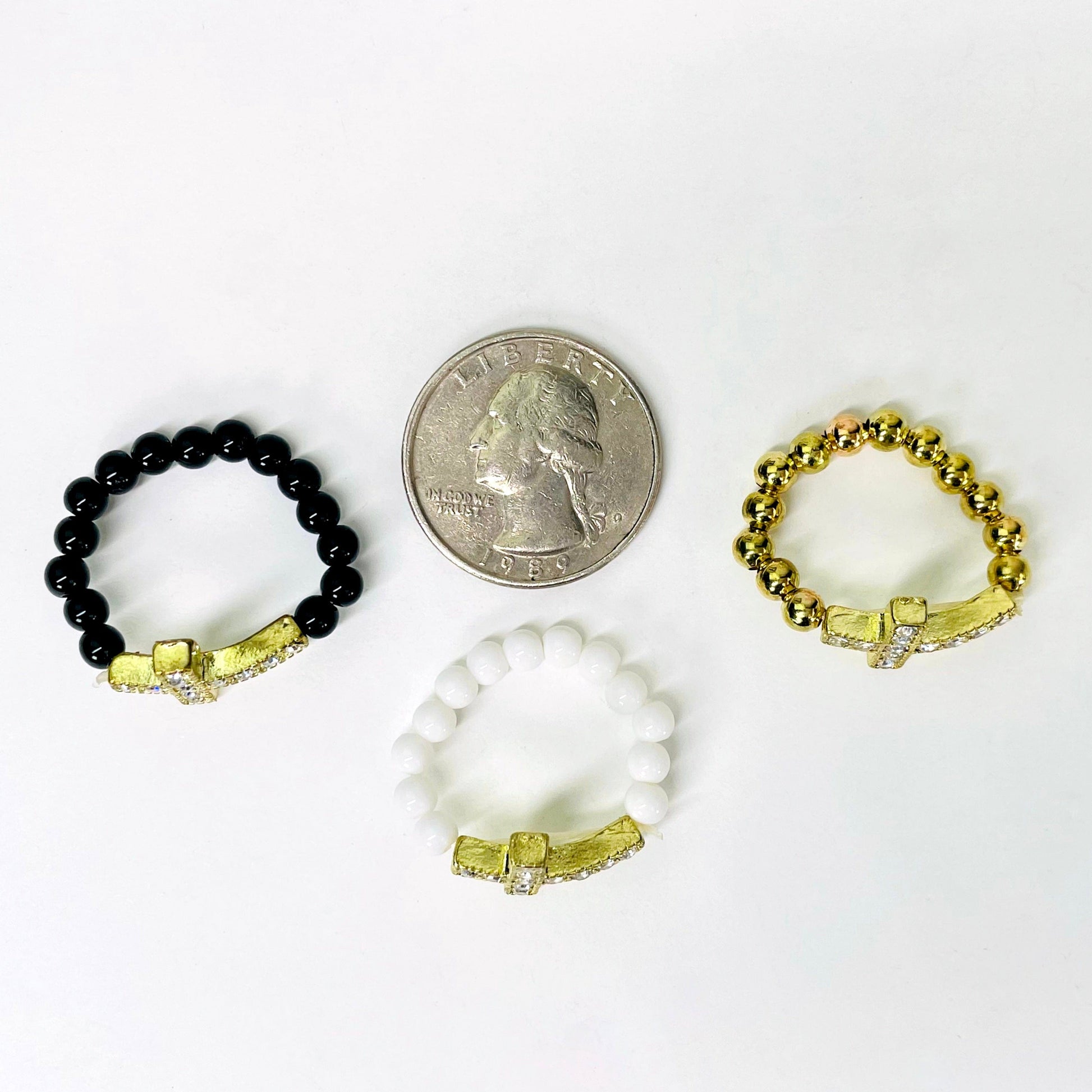 overhead view of one of each sideways cross elastic ring colors with a quarter for size reference