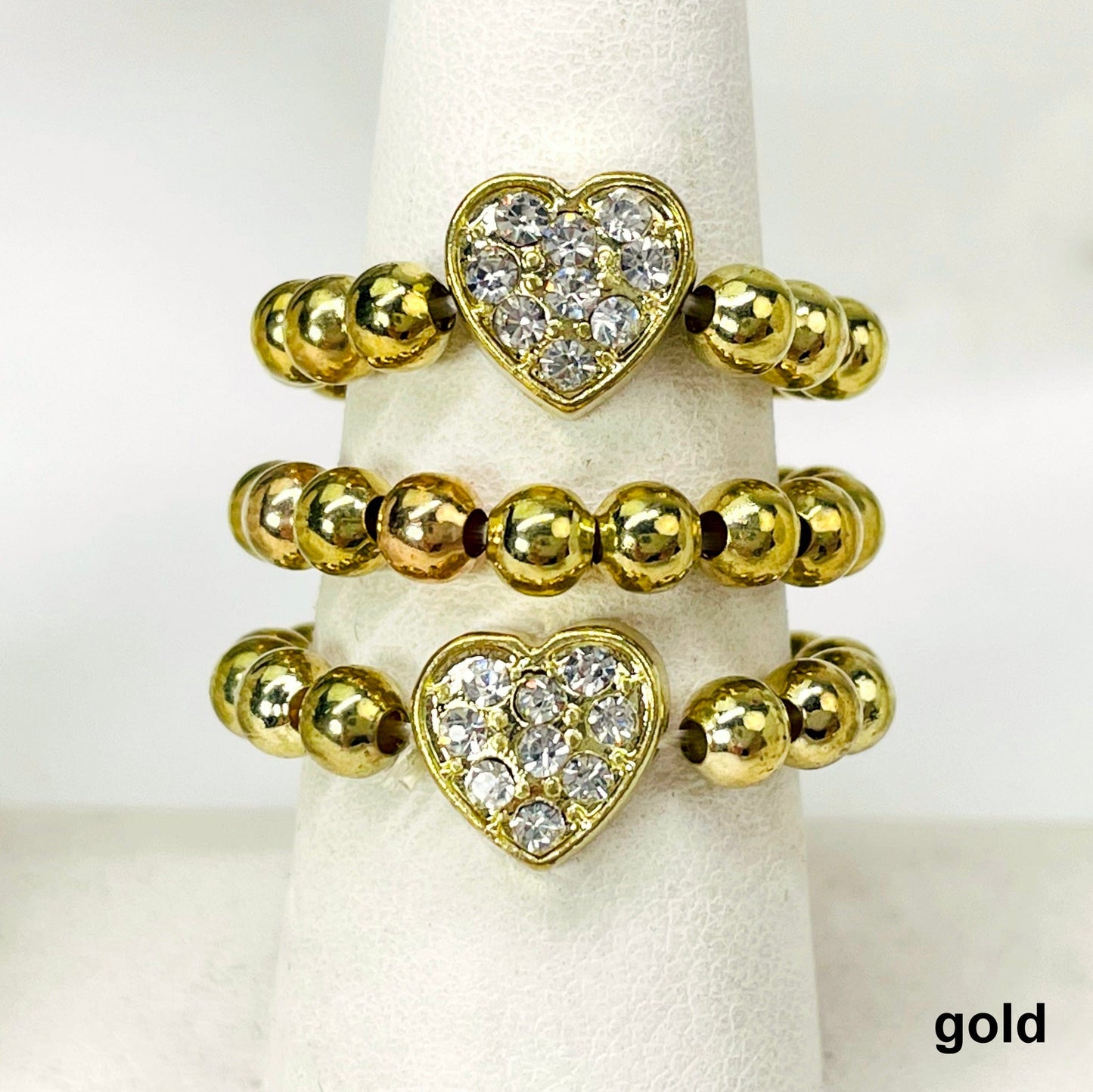 close up of three gold heart elastic rings on ring display