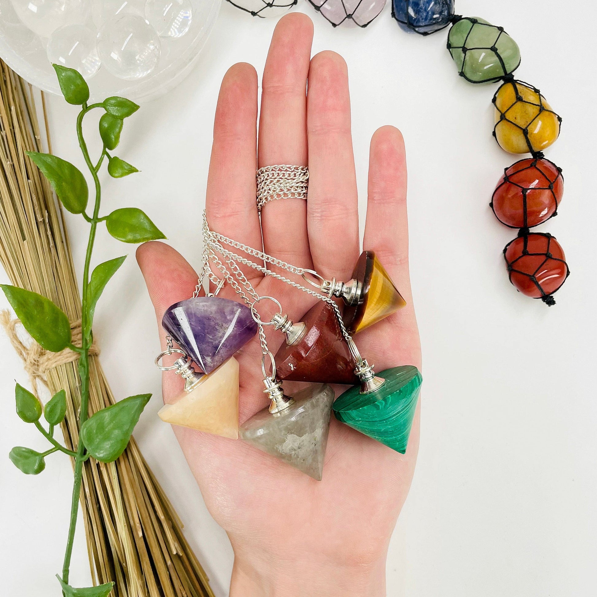 six different pendulum pendants in hand for size reference