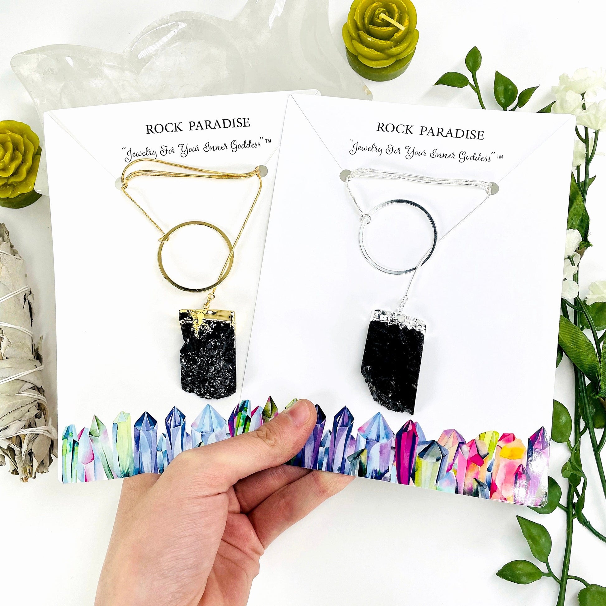 one gold and one silver obsidian chunk adjustable necklace in their packaging in hand for size reference and finish comparison