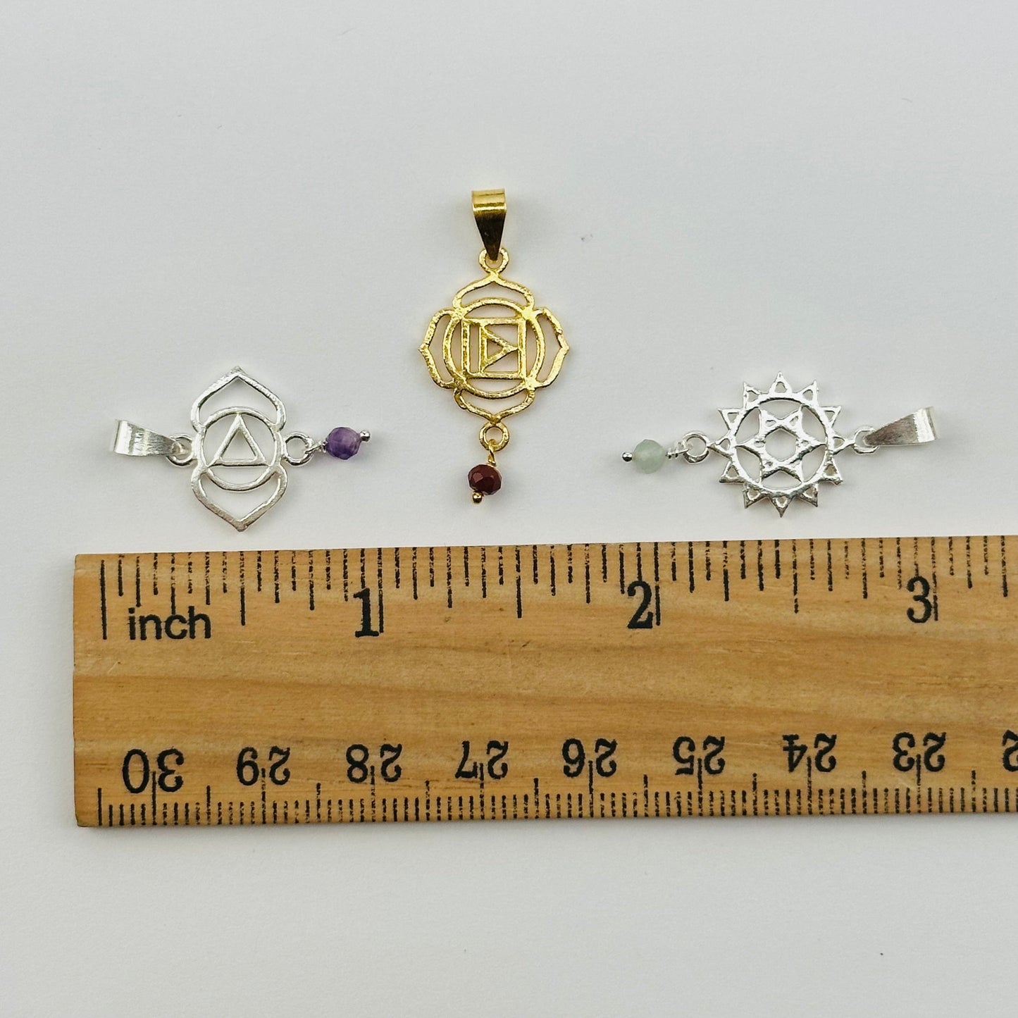 pendants next to a ruler for size reference 