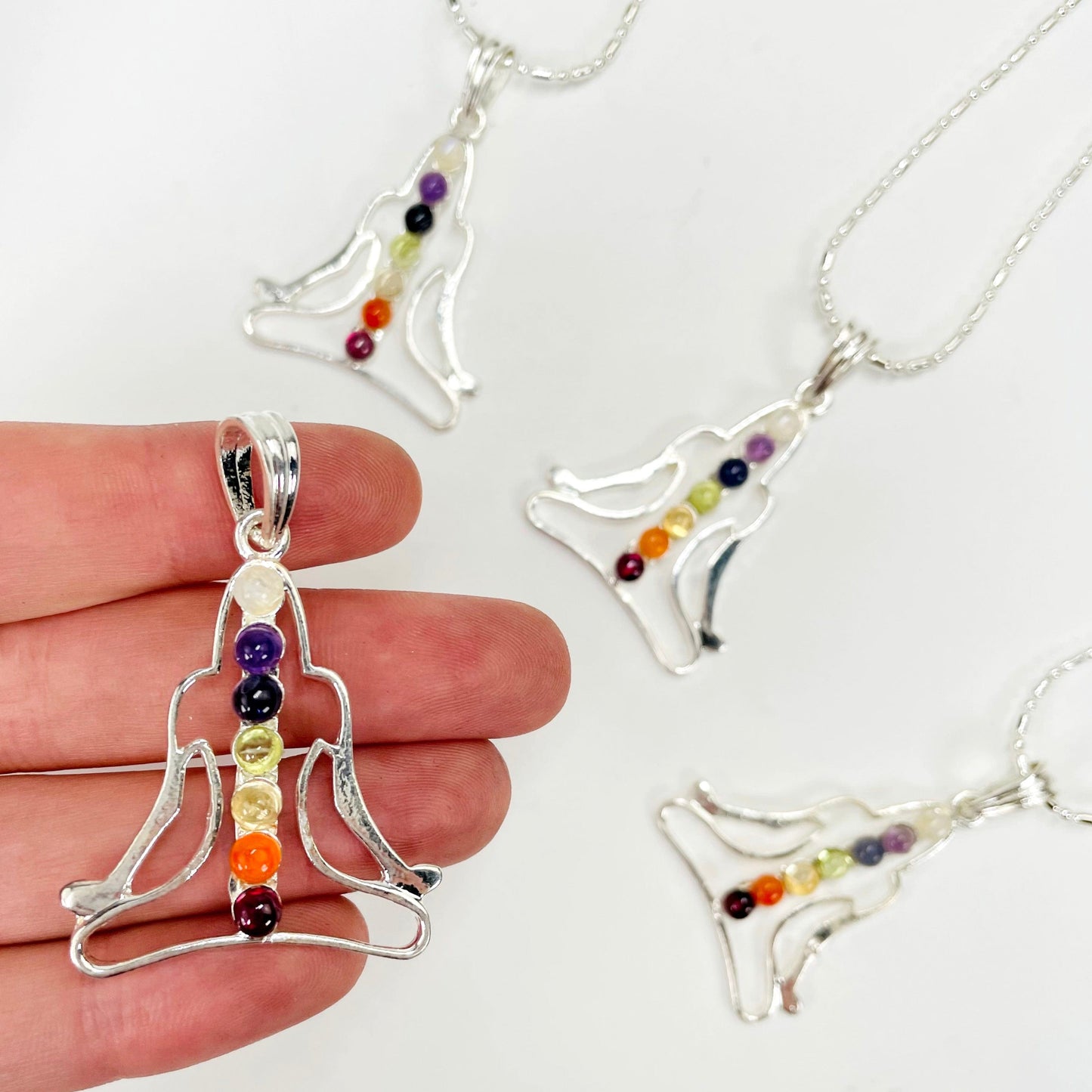 one chakra buddha pendant necklace in hand with three others in the background