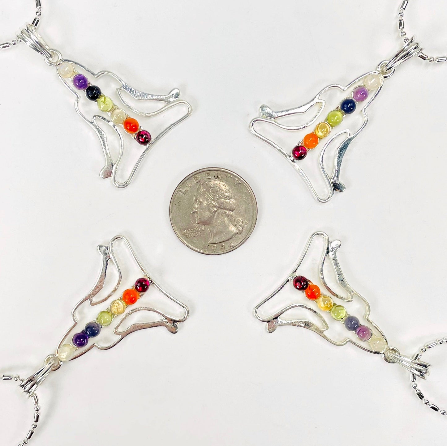 four chakra buddha pendant necklaces surrounding a quarter for size reference