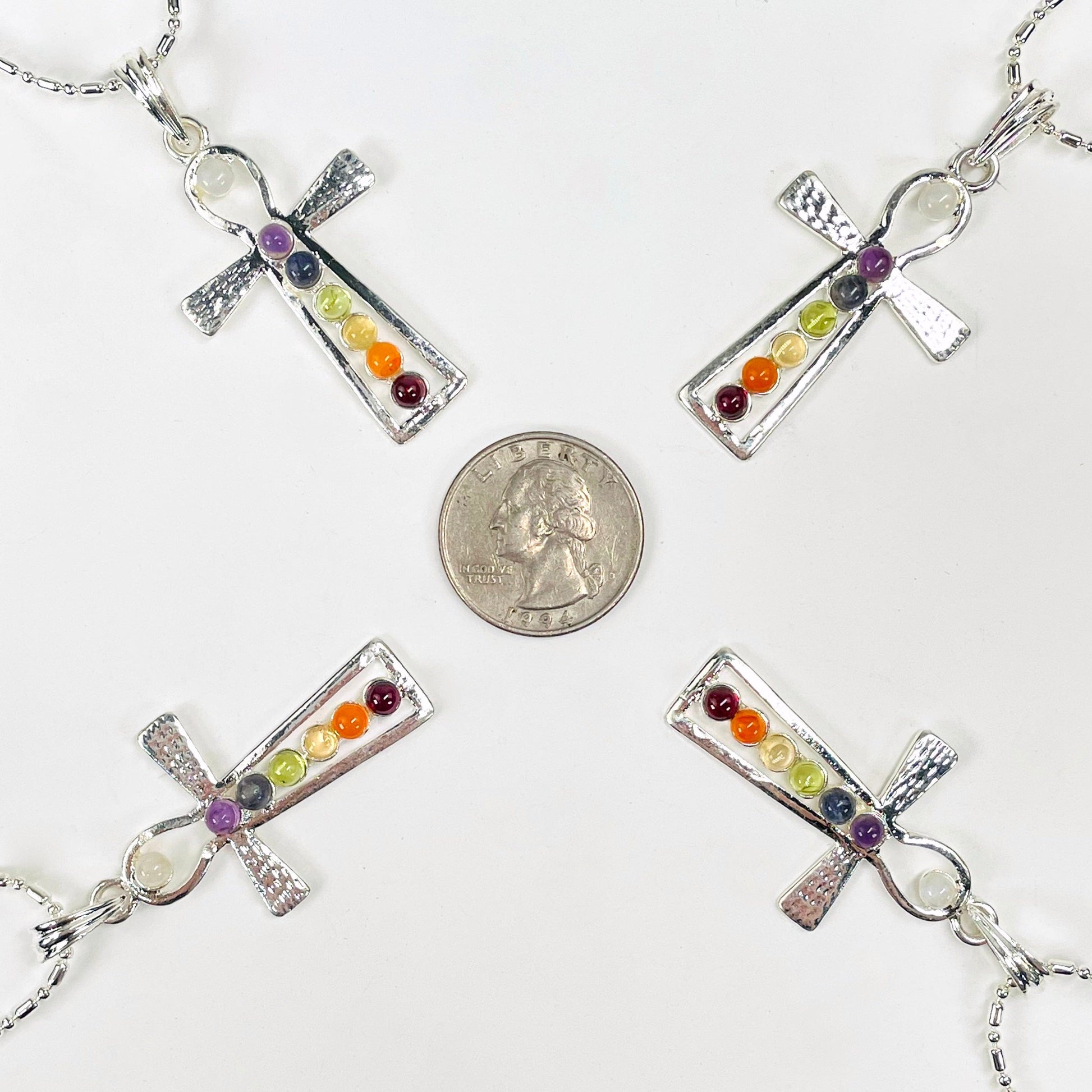 four chakra ankh pendant necklaces surrounding a quarter for size reference