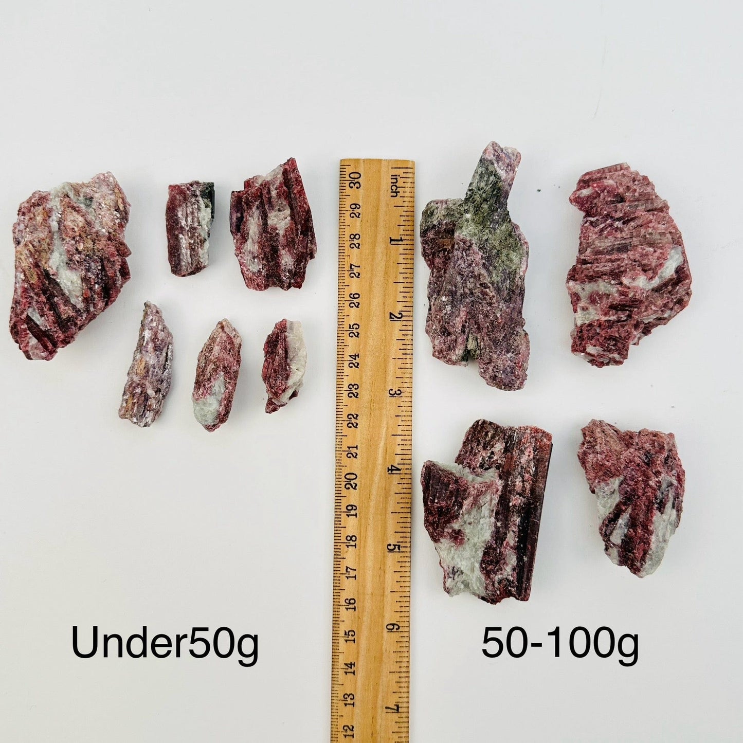 pink tourmaline on aquamarine matrix sold by the weight. displayed next to a ruler for size reference 