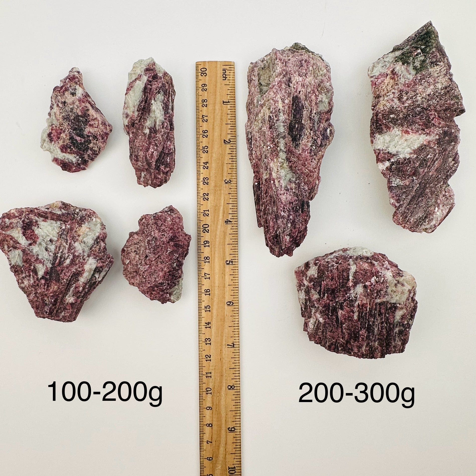 pink tourmaline on aquamarine matrix sold by the weight. displayed next to a ruler for size reference 