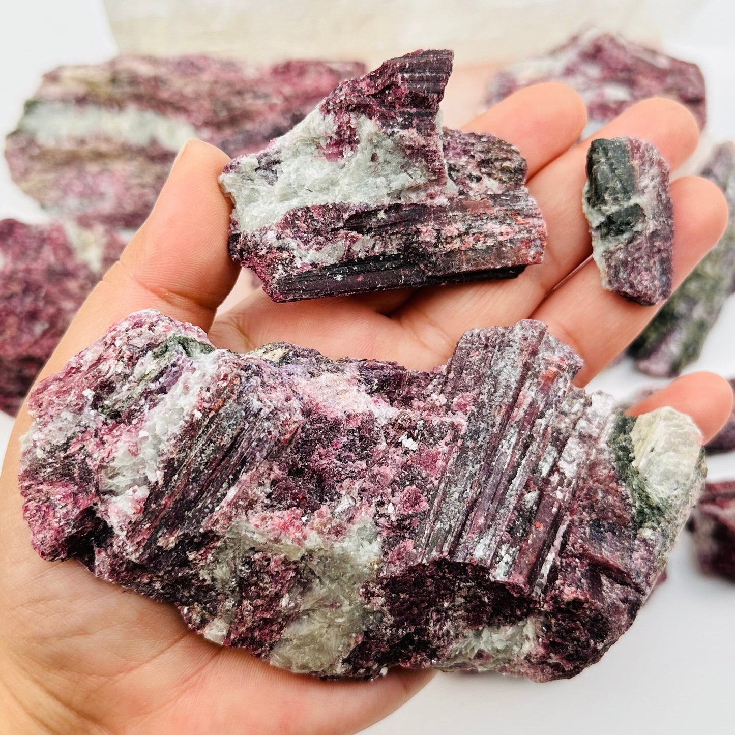pink tourmaline crystal clusters in hand for size reference 