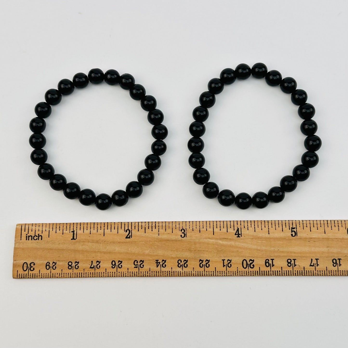 black tourmaline bracelets next to a ruler for size reference 