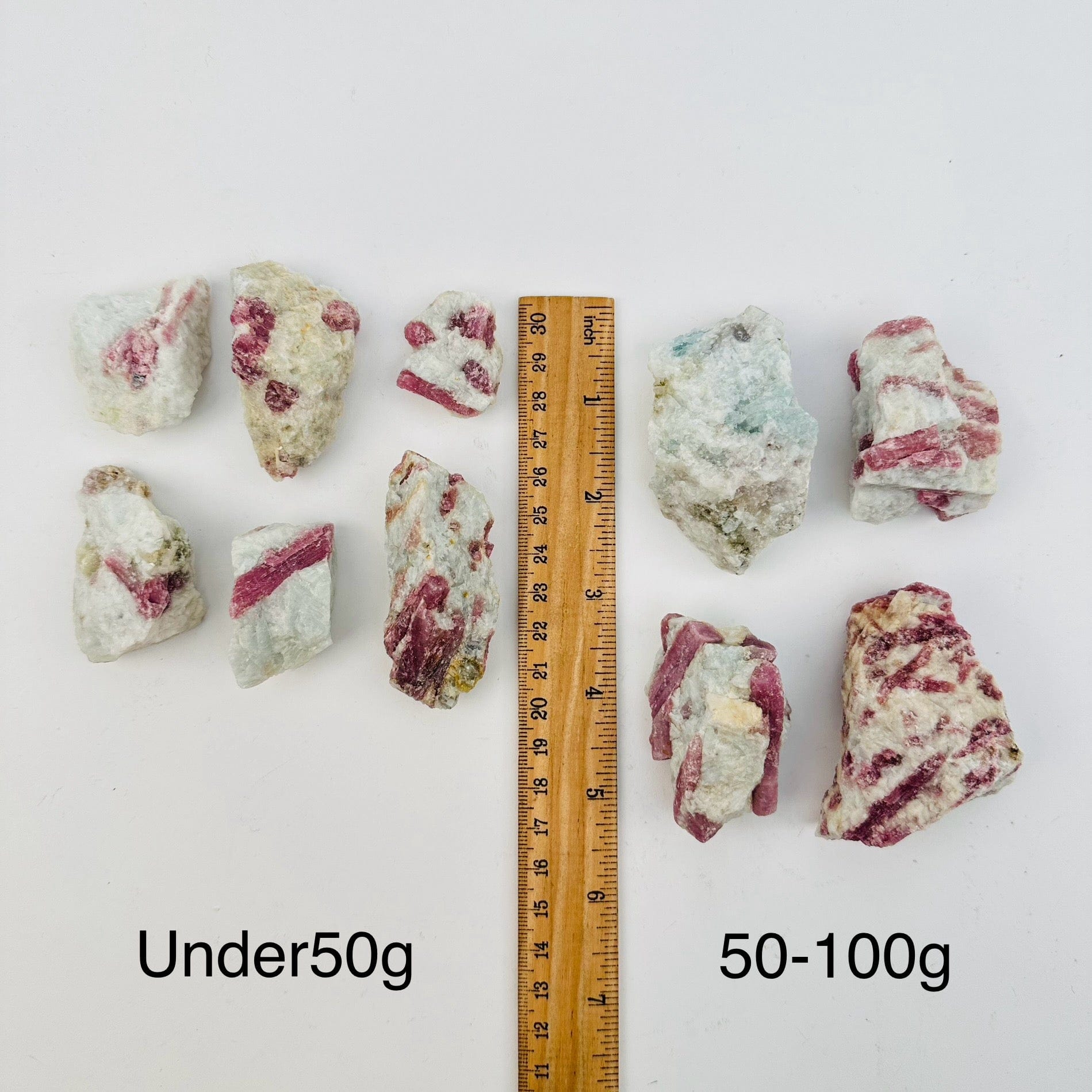 pink tourmaline crystal clusters sold by weight. displayed next to a ruler for size reference 
