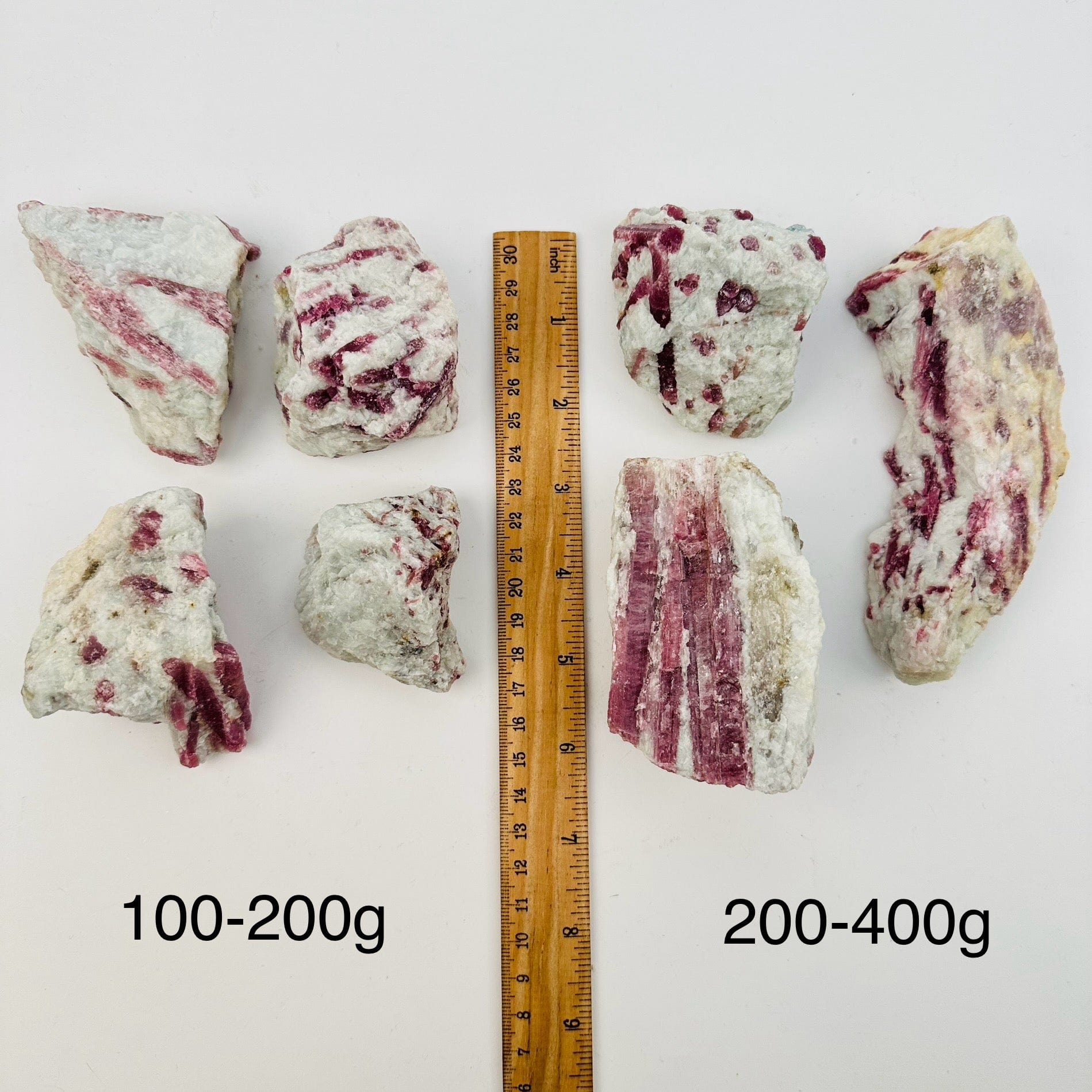 pink tourmaline crystal clusters sold by weight. displayed next to a ruler for size reference 