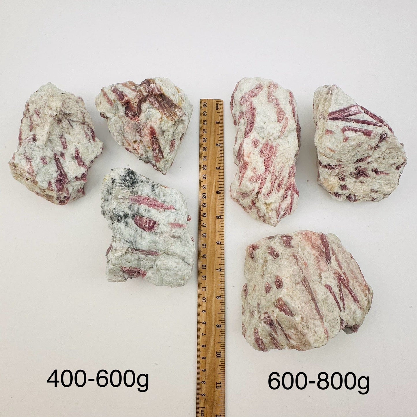 pink tourmaline crystal clusters sold by weight. displayed next to a ruler for size reference 